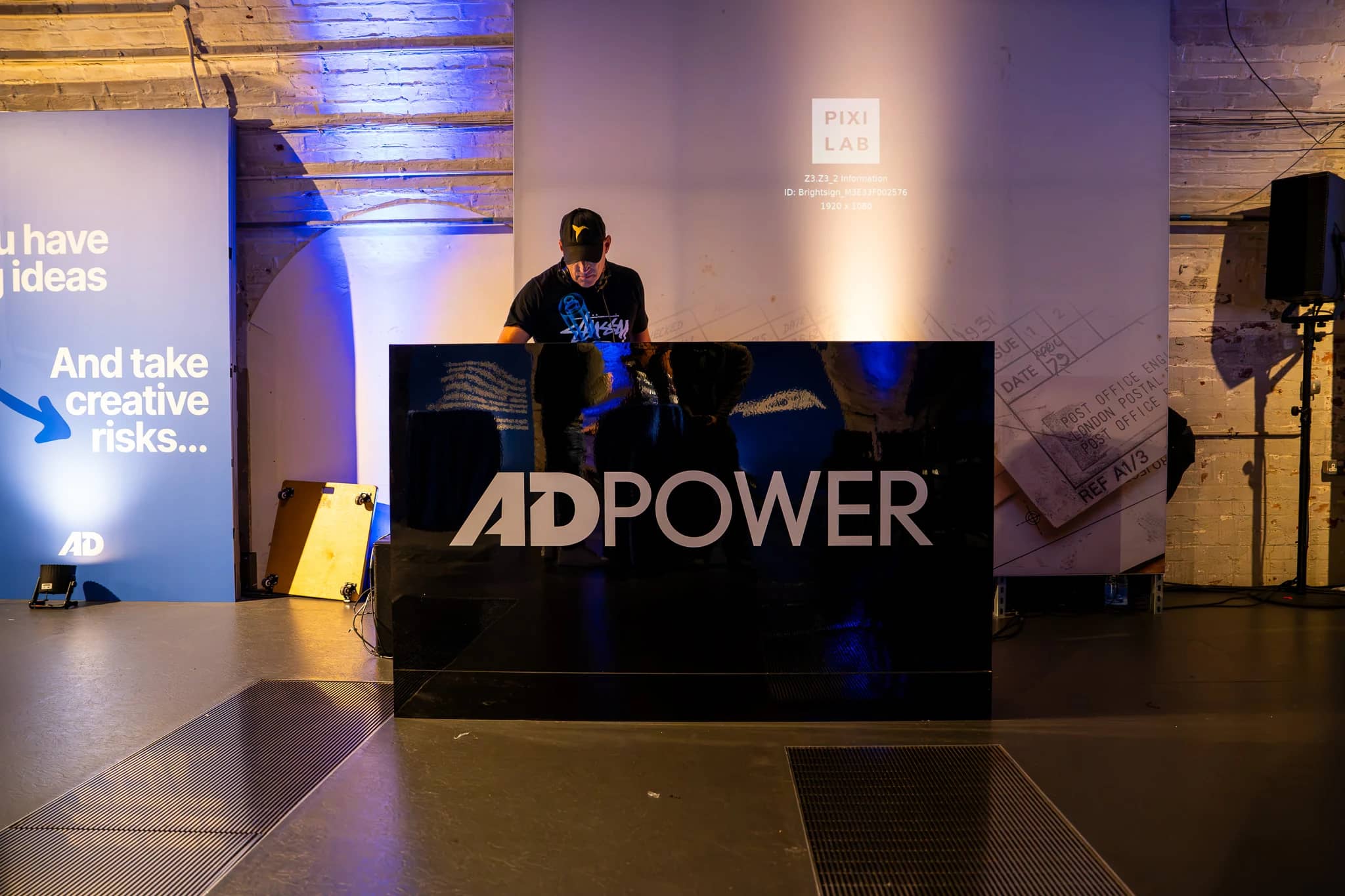 The black DJ booth carrying the white AdPower logo in the Mail Rail event space.