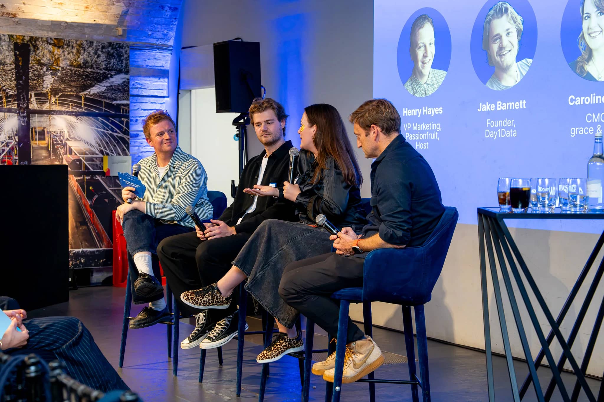 The AdPower panel in conversation with microphones in front of the projected speaker introduction at Mail Rail.