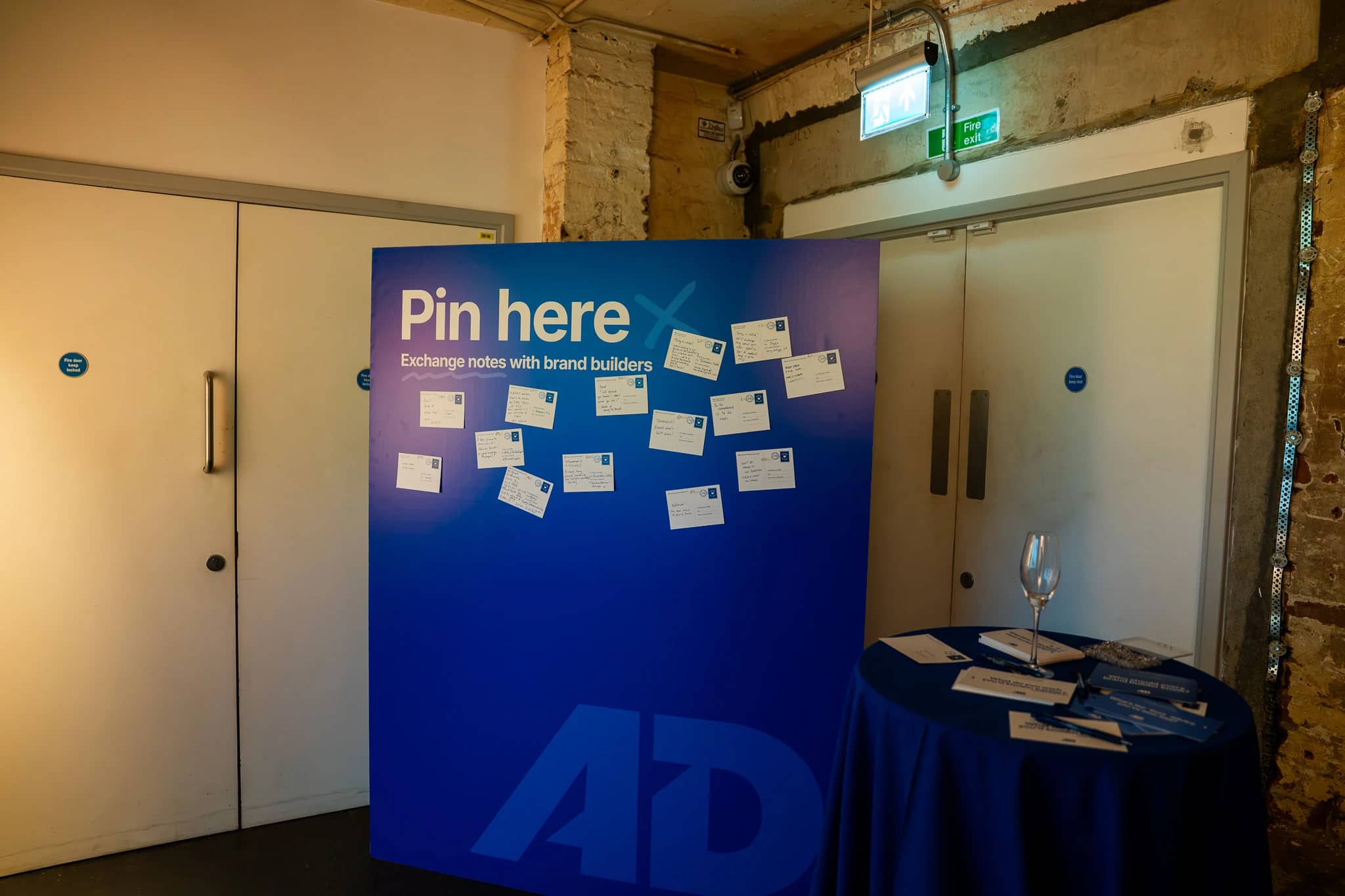 The blue AdPower printed pinboard on its stand with handwritten guest notes and a Pin here heading.