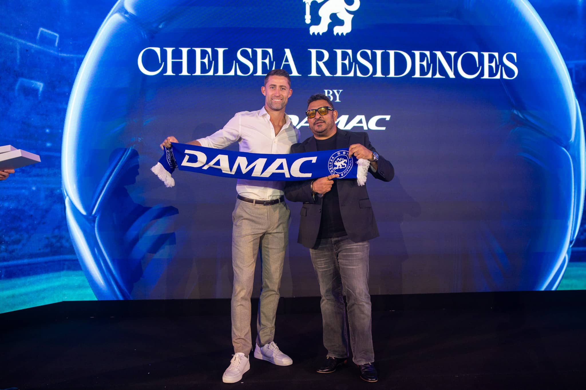 Guests holding a DAMAC scarf on stage in front of the Chelsea Residences LED