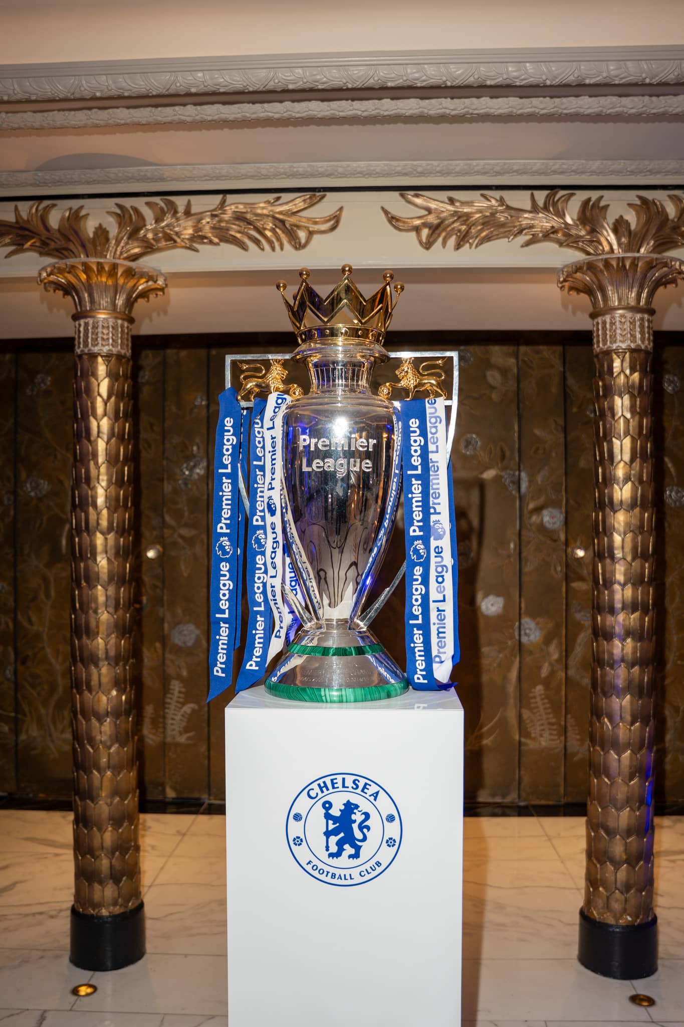 The Premier League Trophy lit on a branded plinth between the columns at The Dorchester