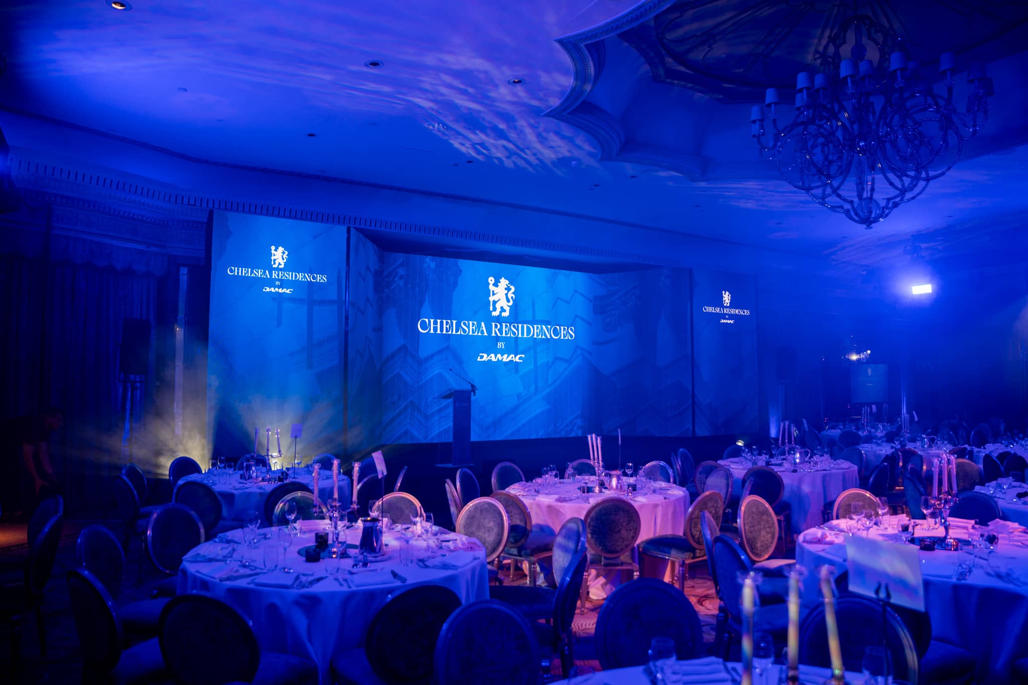 Candlelit guest tables and LED screens in the blue-lit Dorchester ballroom