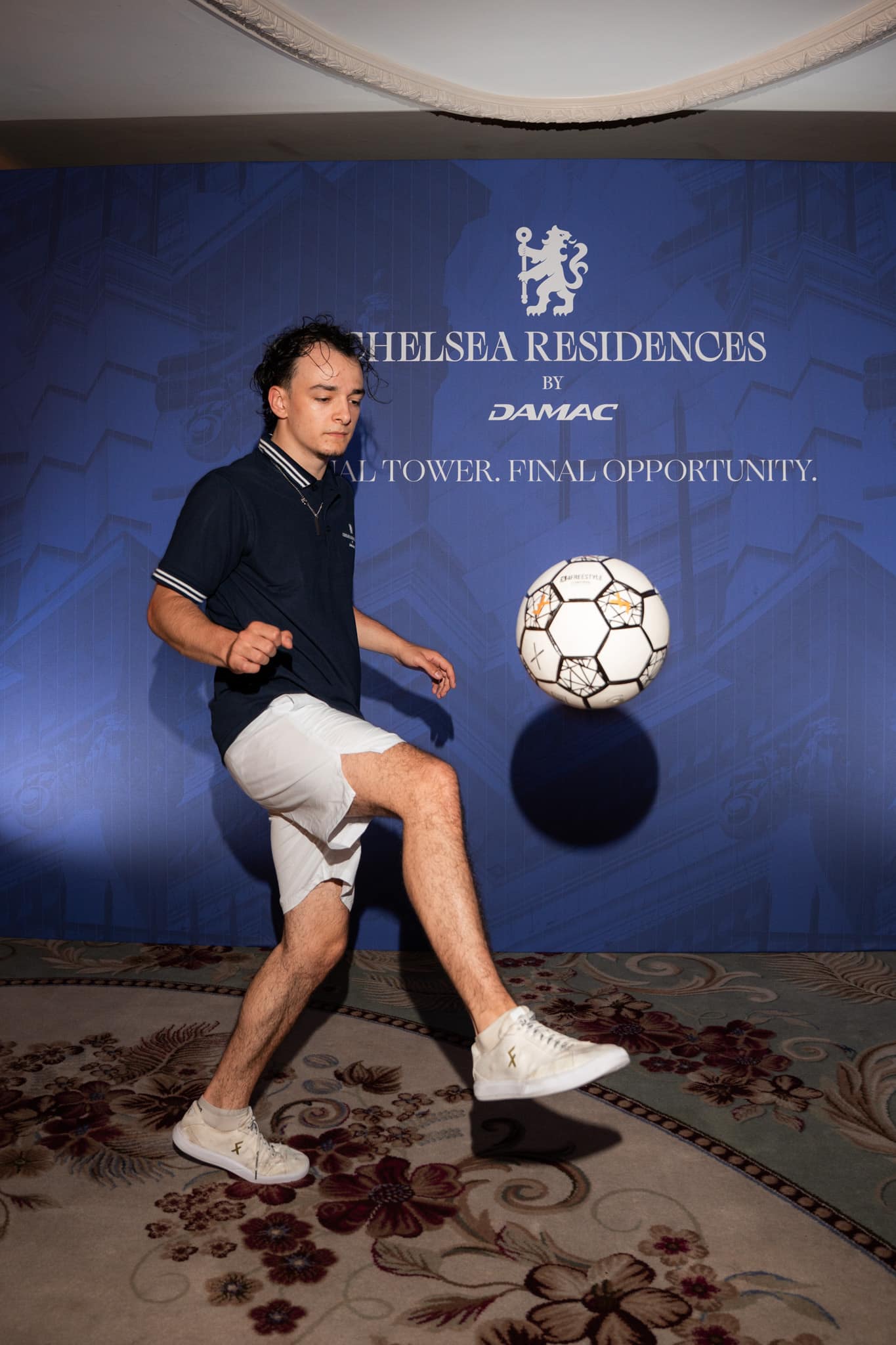 Football freestyler performing in front of the Final Tower printed media wall