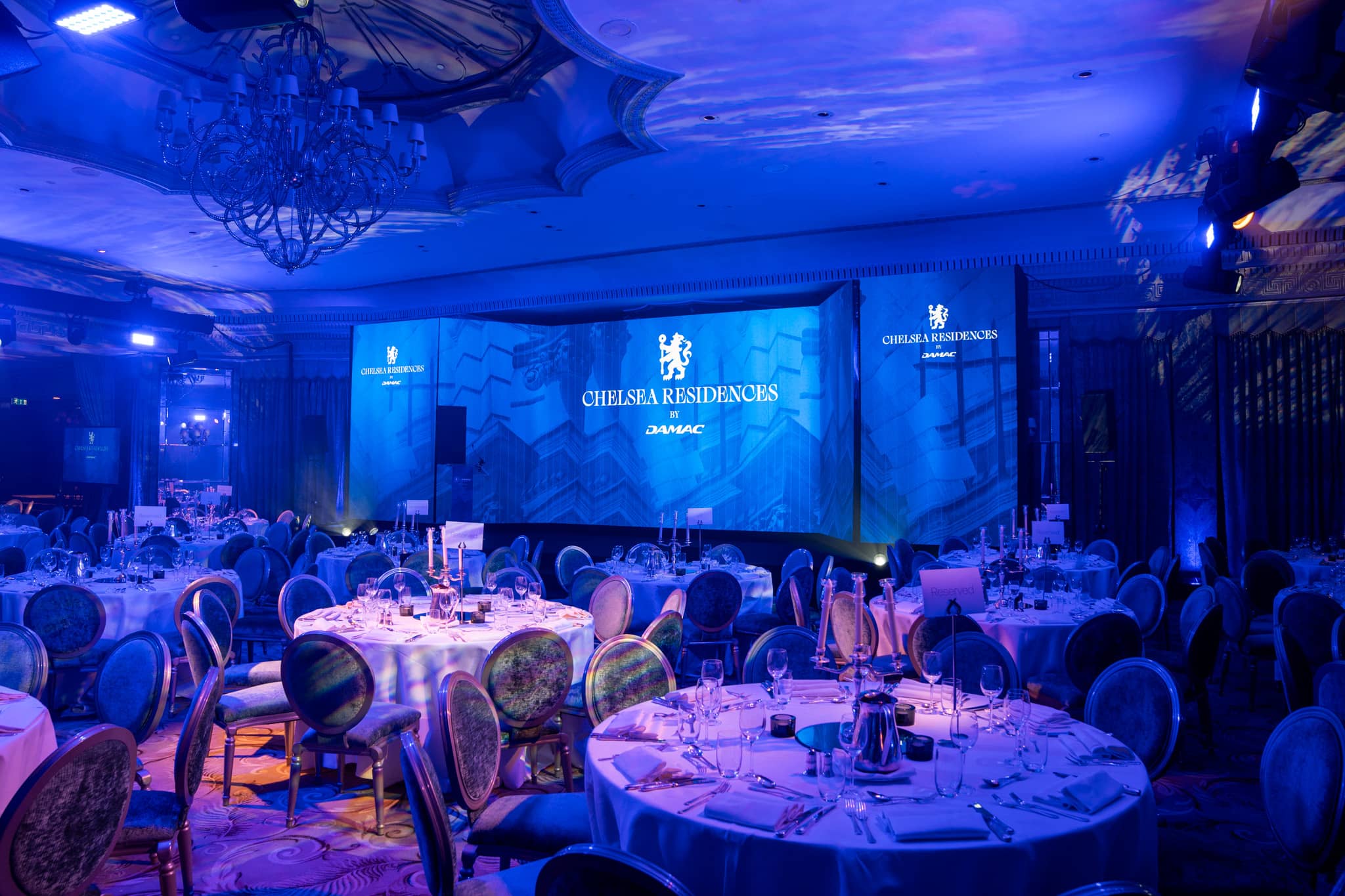 Dressed tables and blue wash lighting across The Dorchester ballroom before guests arrive