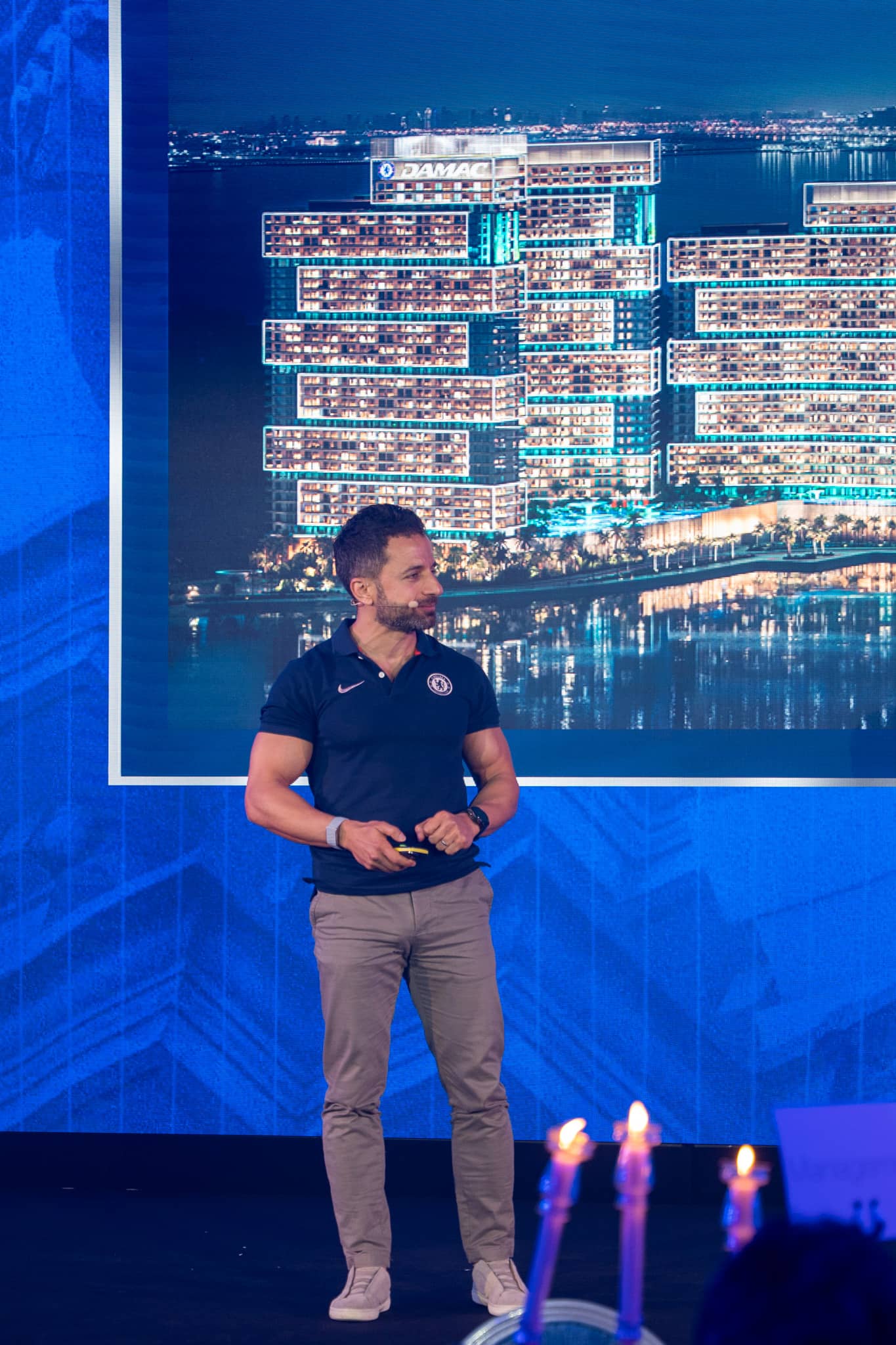 A presenter walking guests through the development, tower render on the LED behind
