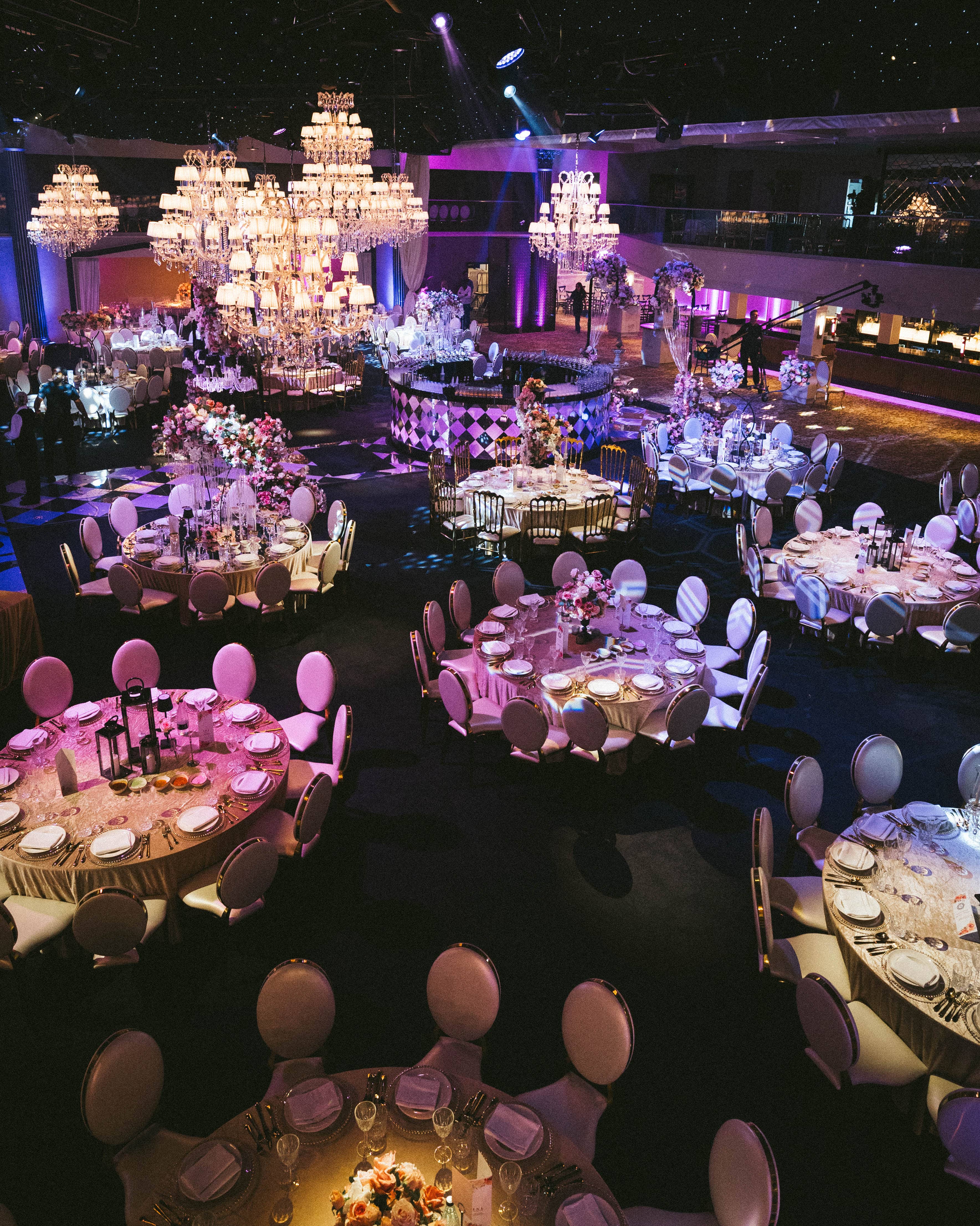 Crystal chandeliers hanging low over the dining tables, by Kudos AV