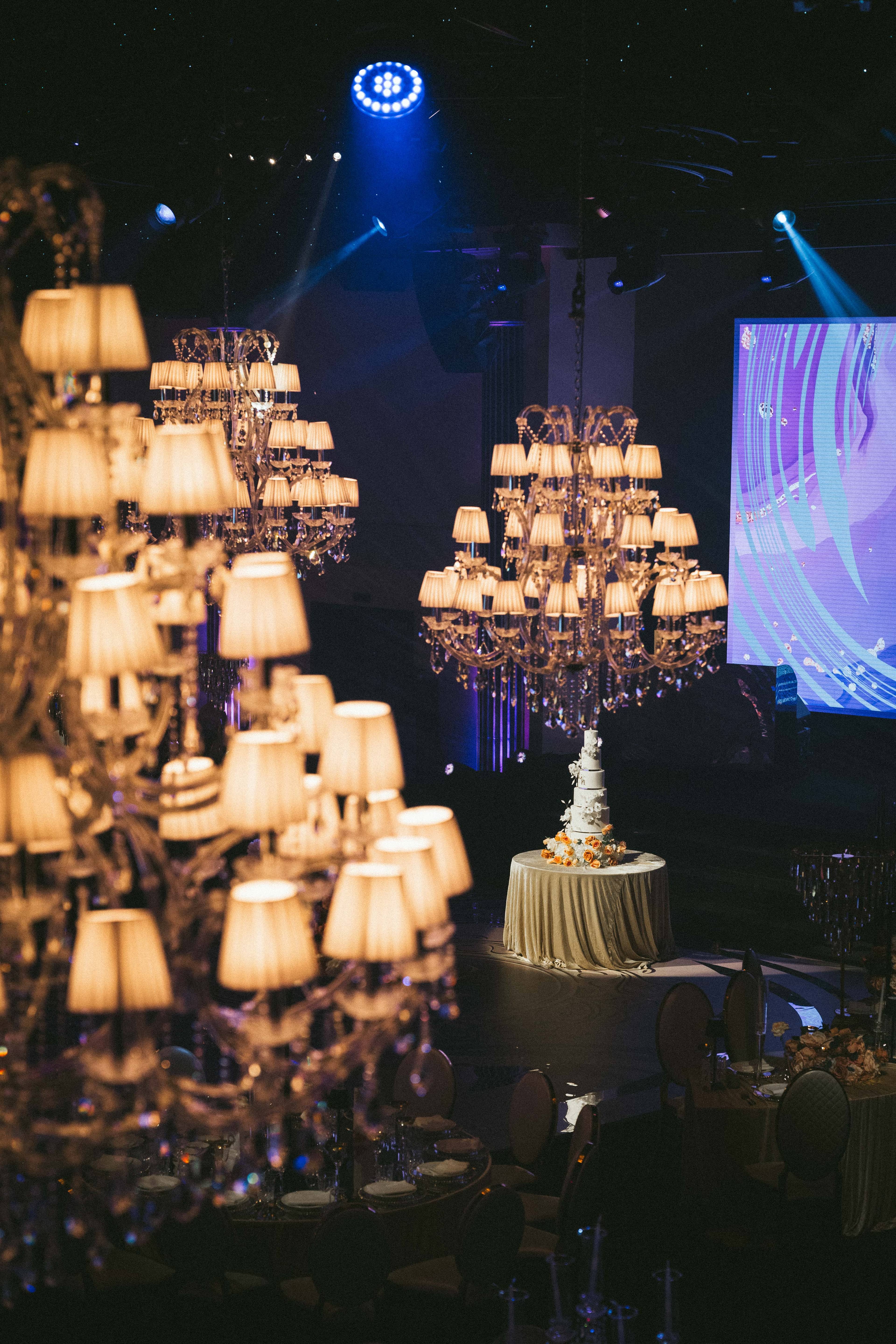 A cluster of shaded chandeliers beside the LED screen, by Kudos AV