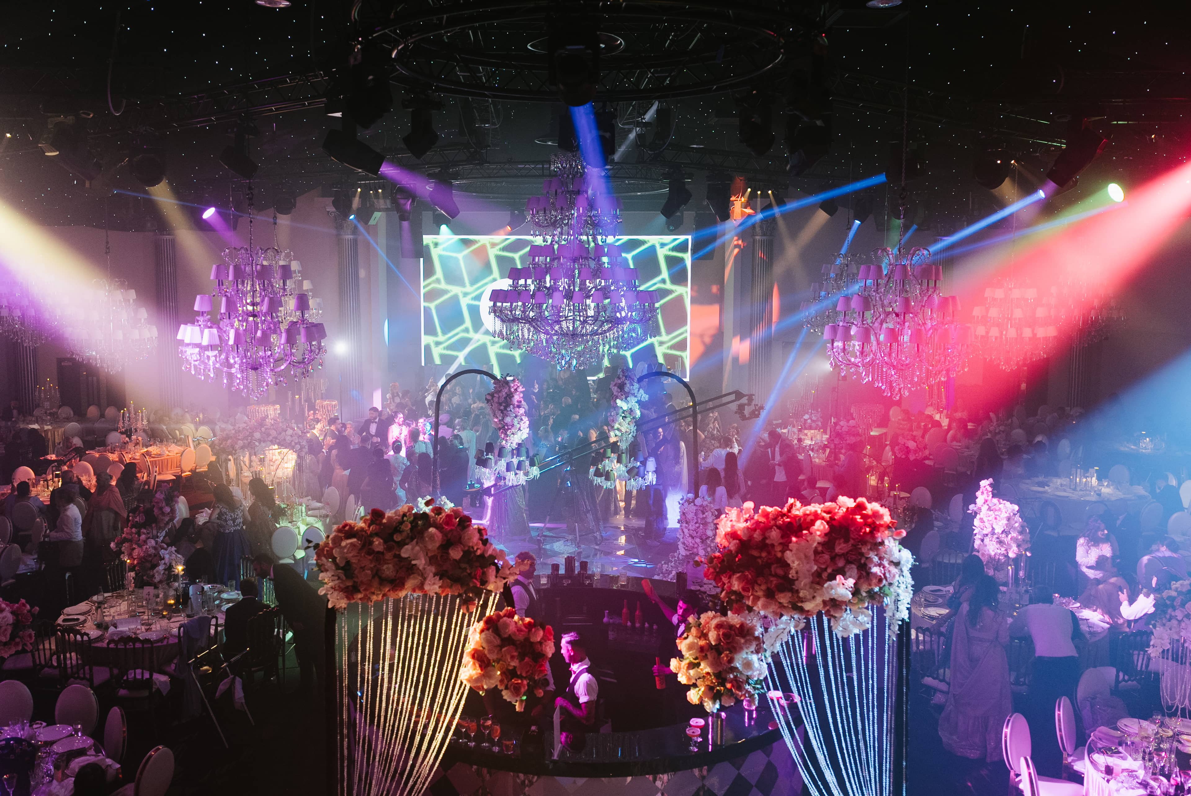 Magenta and cyan beam lighting over florals and the LED screen, by Kudos AV