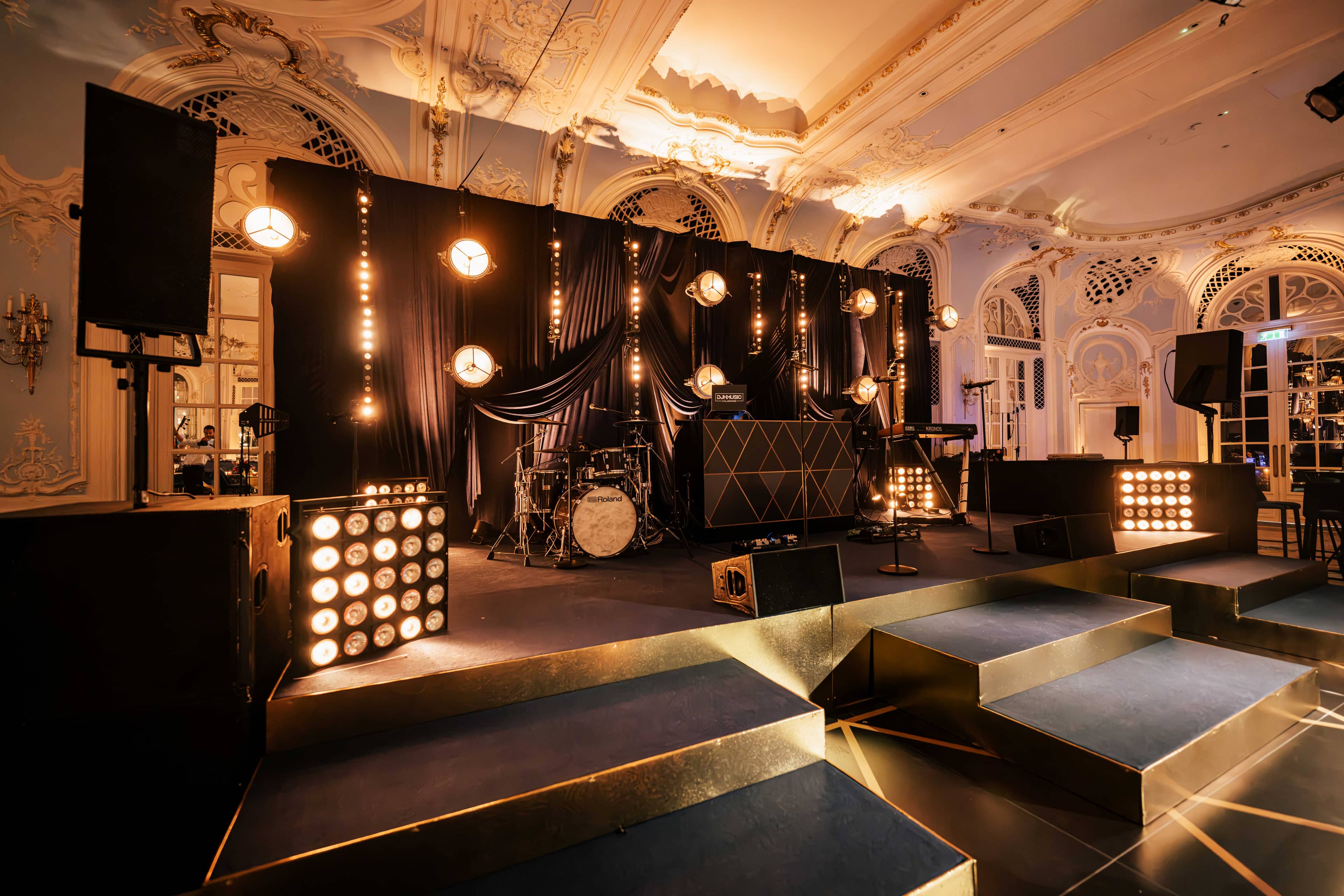 The gold-edged stage and steps at The Savoy, Portman lamps and sunstrips behind, by Kudos AV