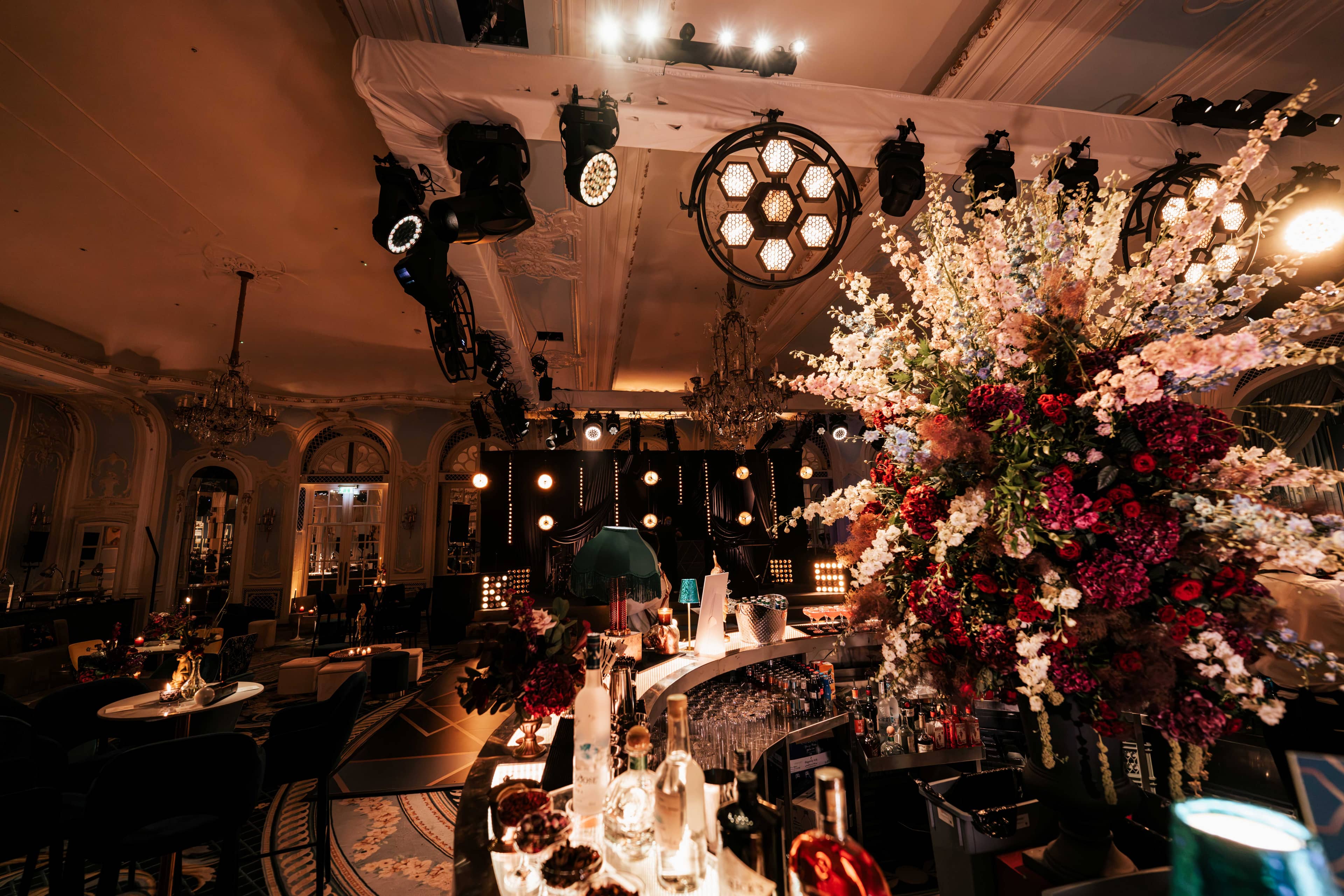 A retro lamp fixture over florals and chandeliers at The Savoy wedding, by Kudos AV