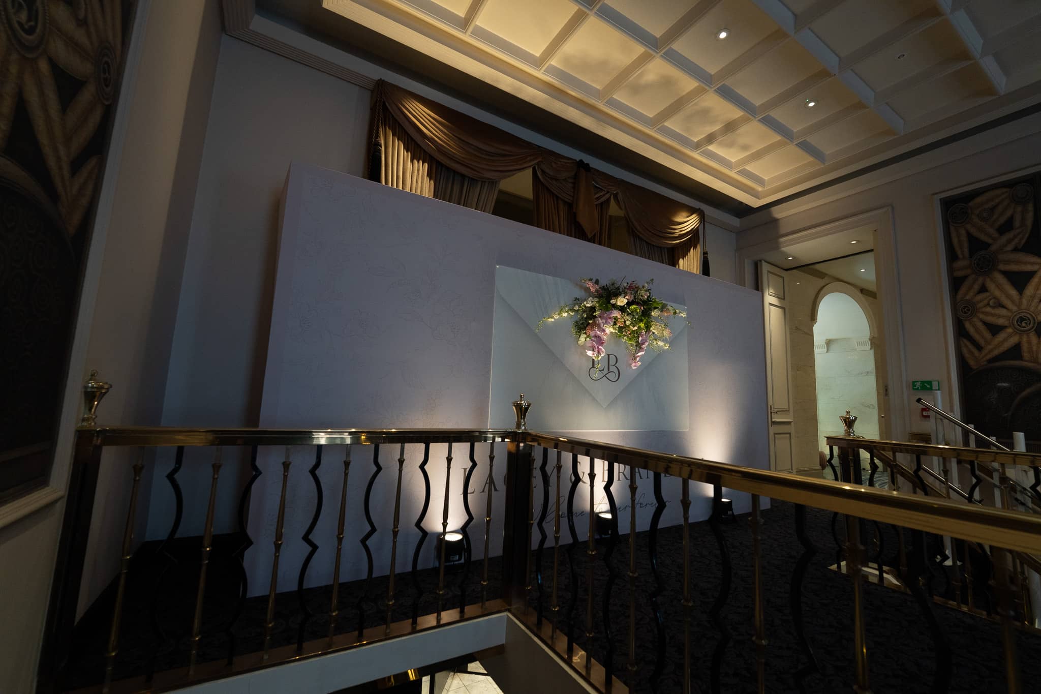 The printed media wall wide beneath the coffered ceiling at The Savoy with the brass balustrades in front, built and installed by Kudos AV