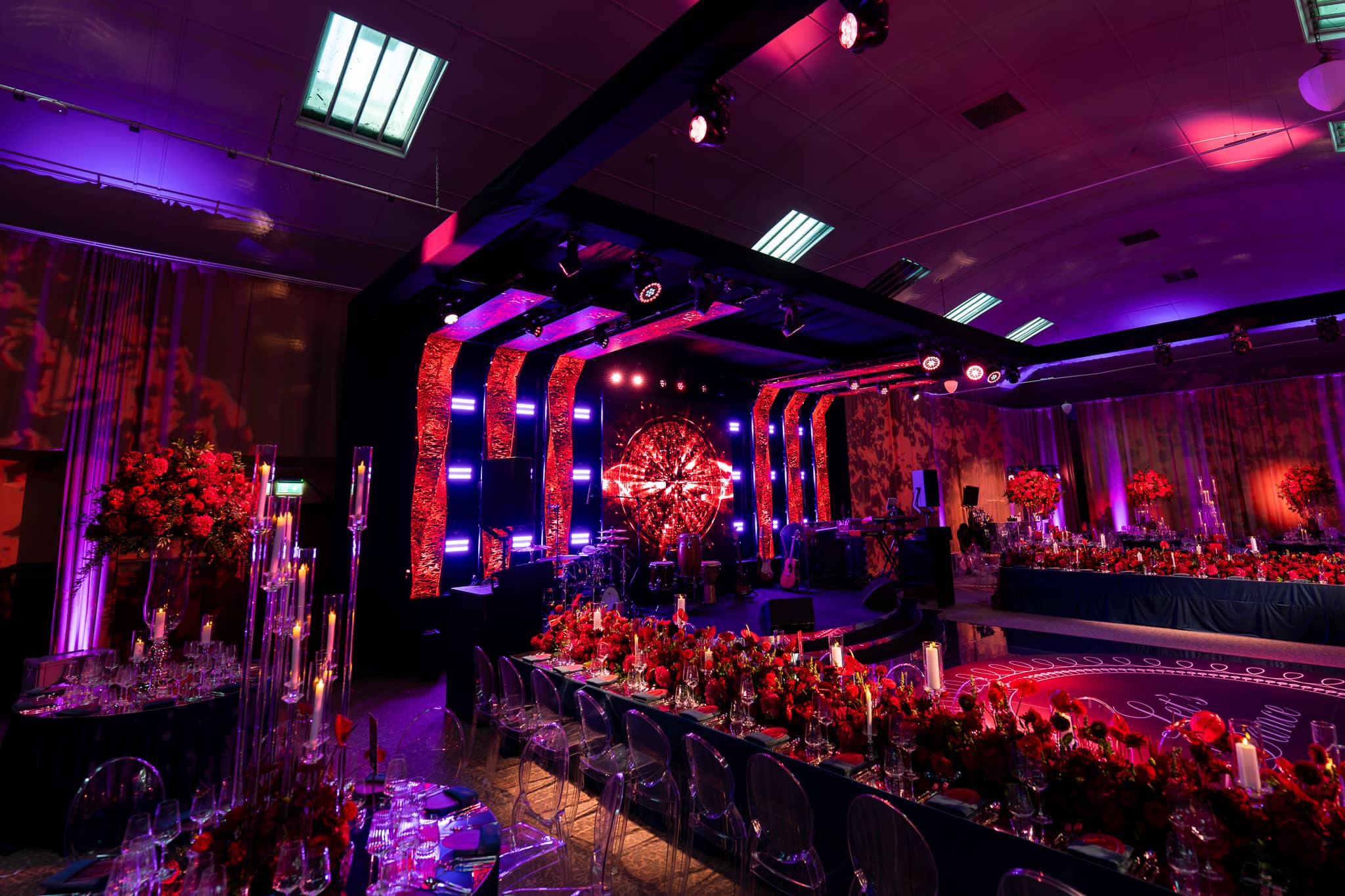 Tatton Park wedding in the Tenants' Hall, the transformed hall with red florals and lit arches, produced by Kudos AV