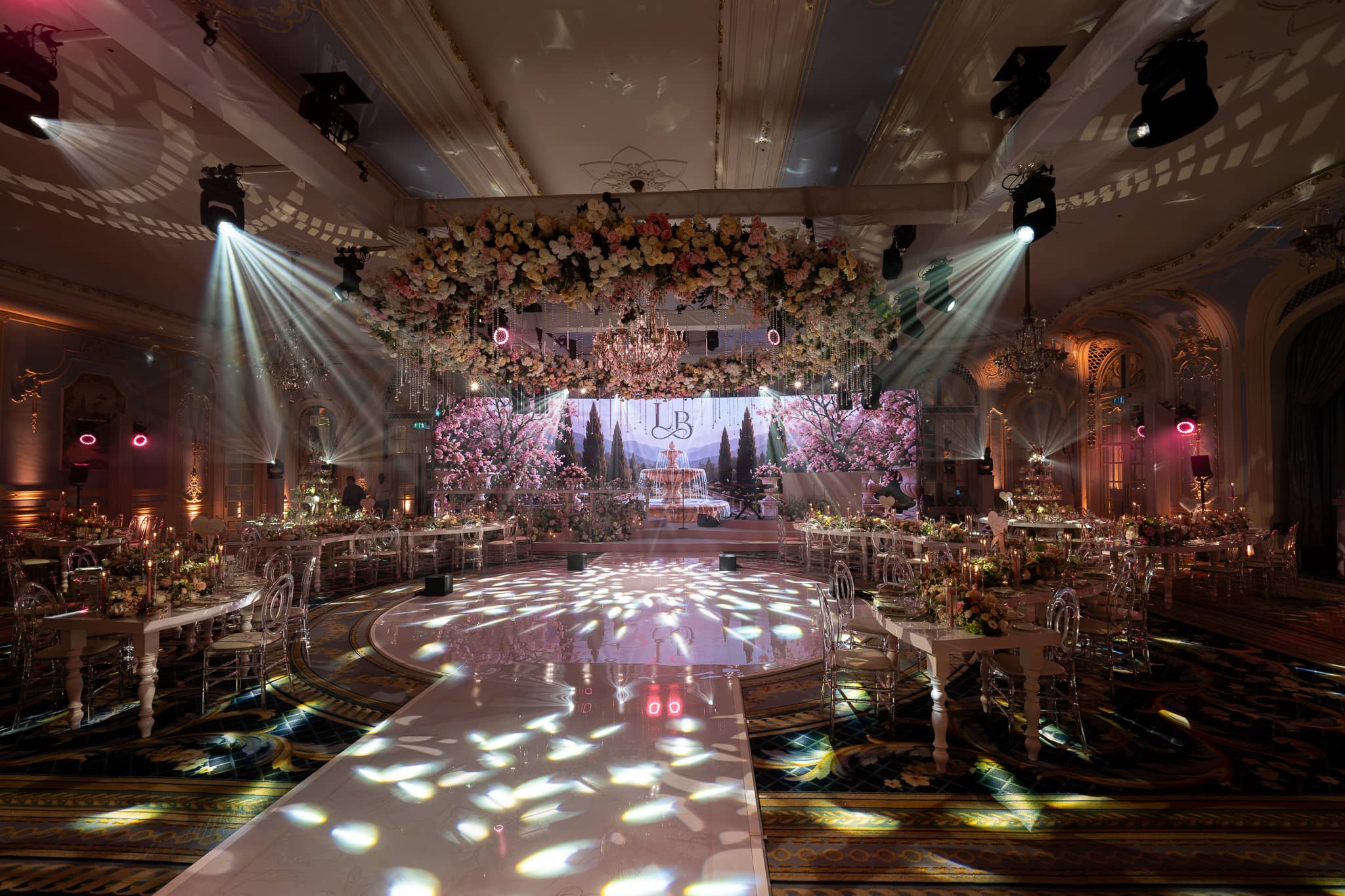 The shaped walkway and dancefloor running to the stage in the Lancaster Ballroom at The Savoy, floral canopy overhead and blossom content on the curved LED, by Kudos AV