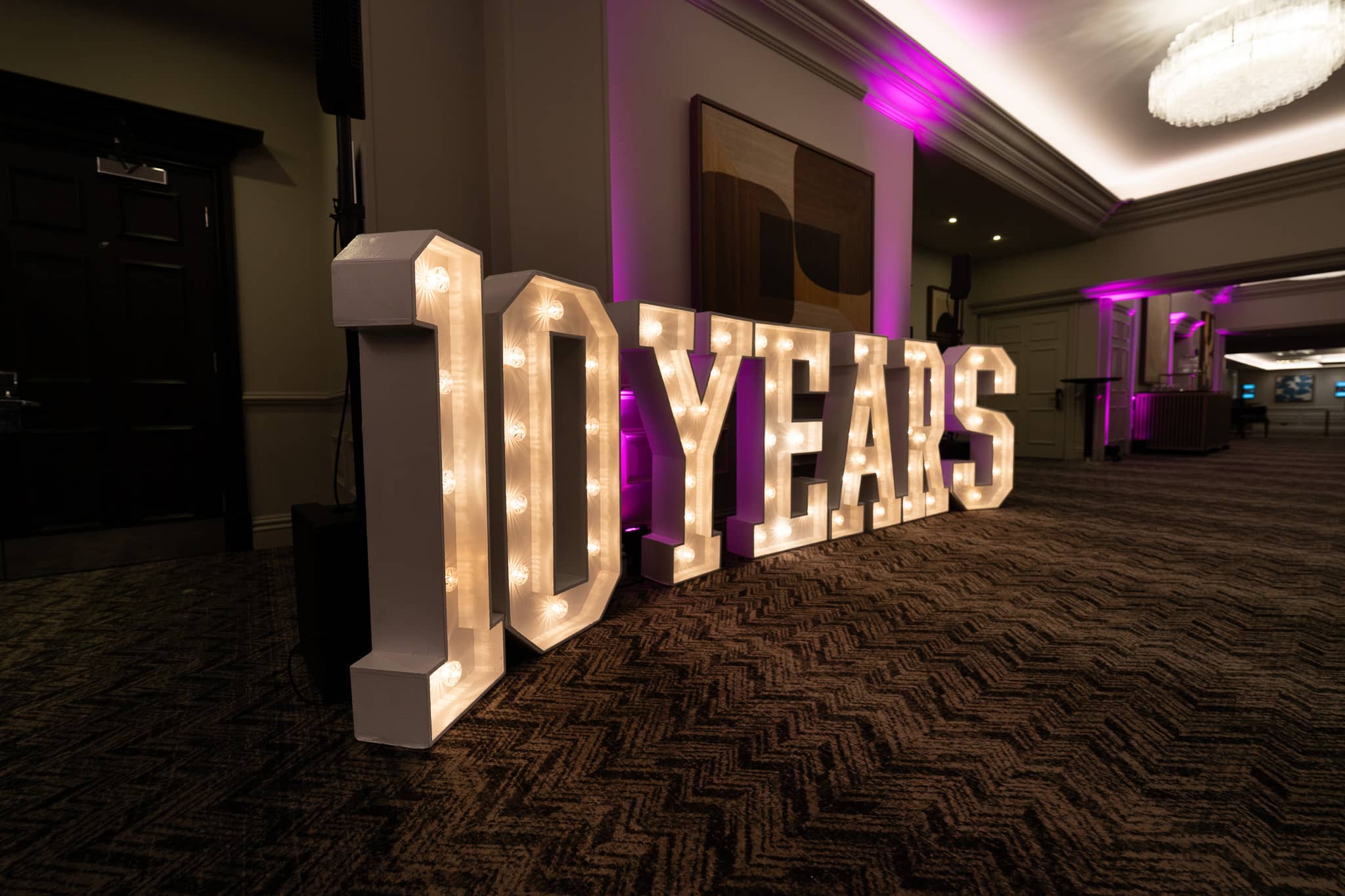 Angled view of the 10 YEARS marquee letters with pink uplighting along the foyer at Sopwell House for Verve Awards Night.