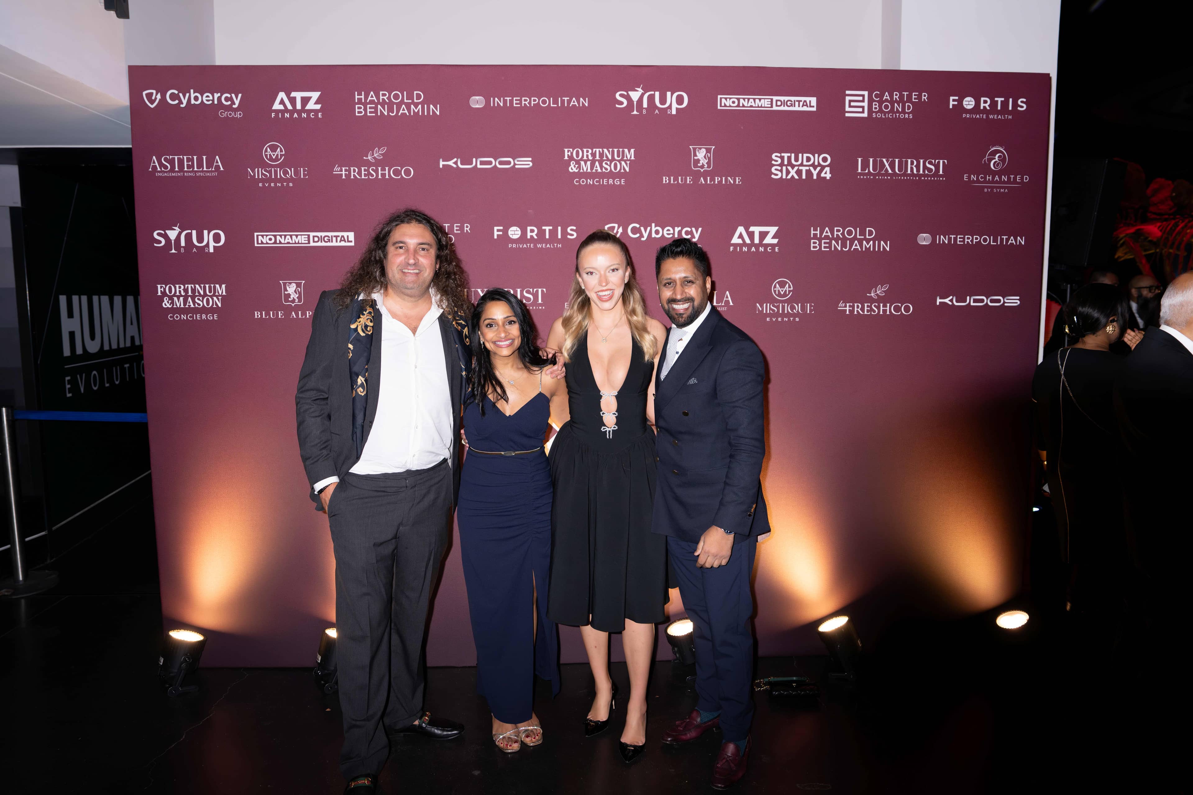 Four guests at the FOUNDXRS Club photo call under warm light, FOUNDXRS Club black tie party in Earth Hall at the Natural History Museum.