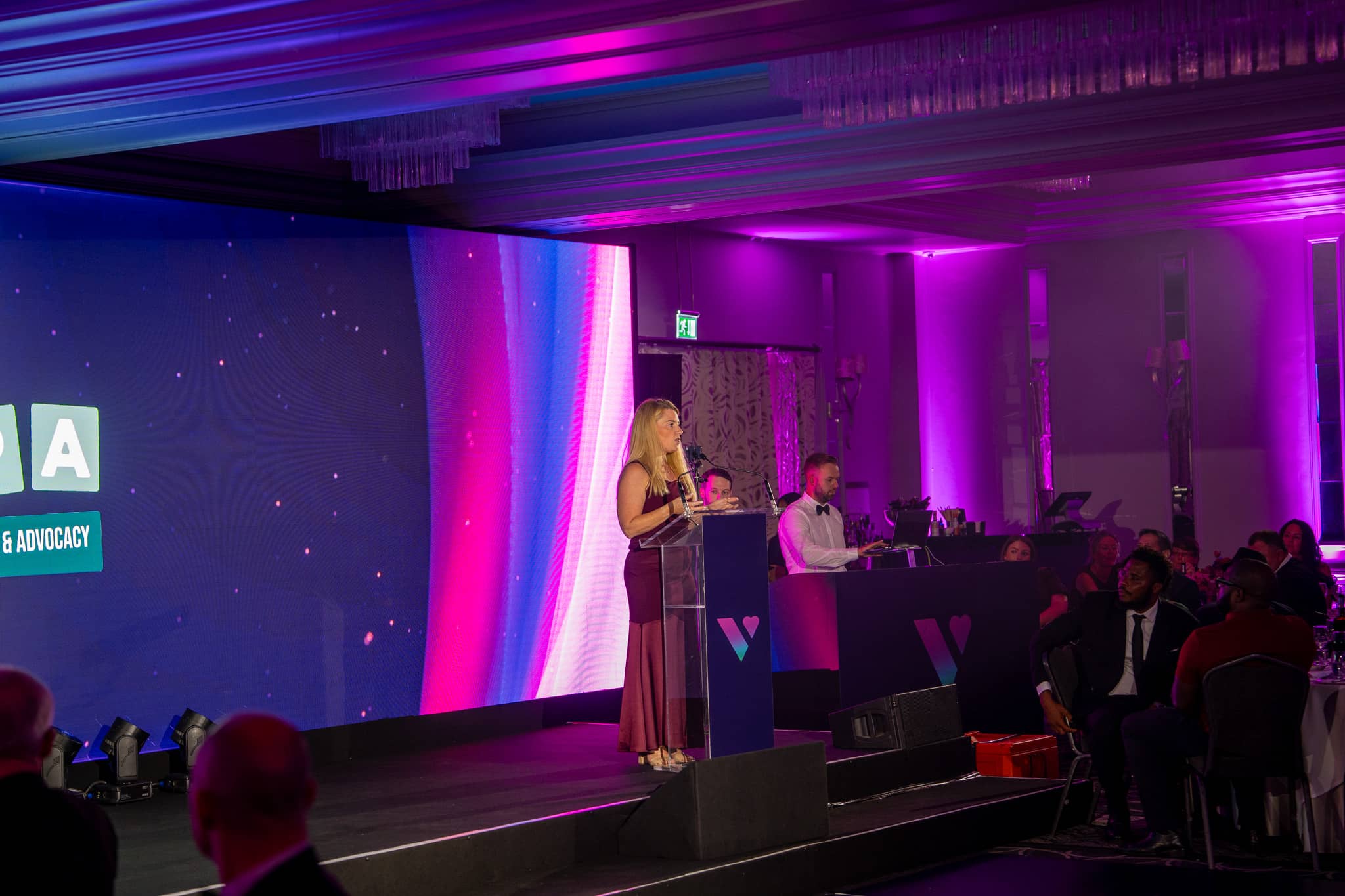 A speaker presents at the lectern with the CASPA charity logo on the LED wall during Verve Awards Night in the St Alban Suite at Sopwell House.