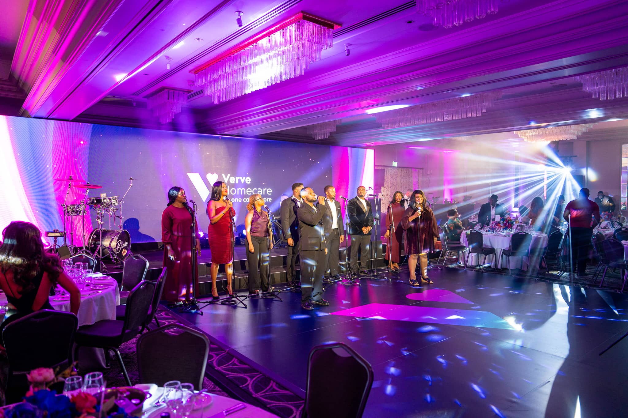 The gospel choir and band perform for guests in the St Alban Suite at Sopwell House, with beam lighting, the Verve Homecare LED wall and the branded dancefloor.