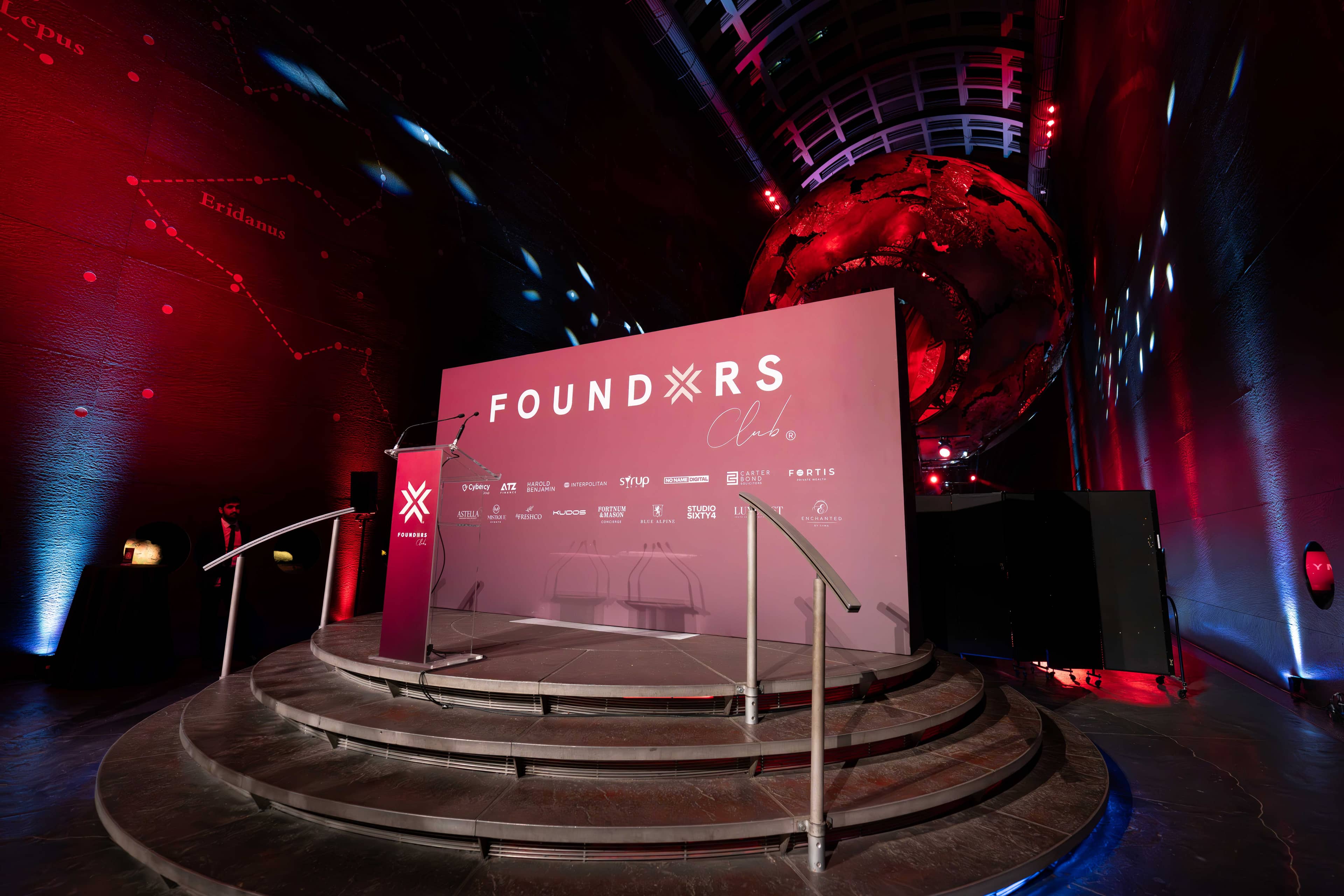 The FOUNDXRS stage under the Earth sculpture, red and blue light across Earth Hall, FOUNDXRS Club black tie party by Kudos AV.