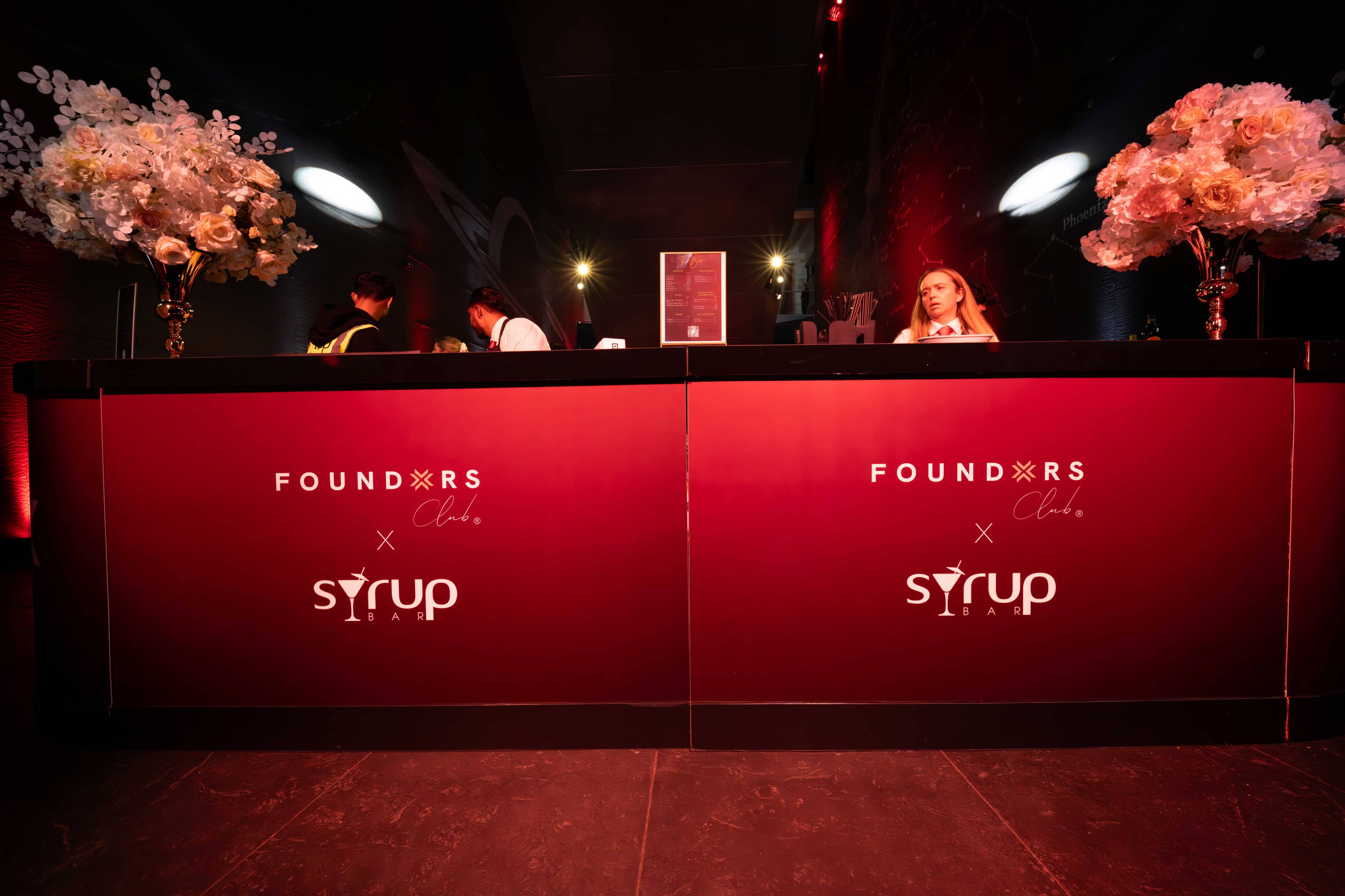 The illuminated red bar with FOUNDXRS Club branding and coral florals at the FOUNDXRS Club black tie party in Earth Hall, by Kudos AV.