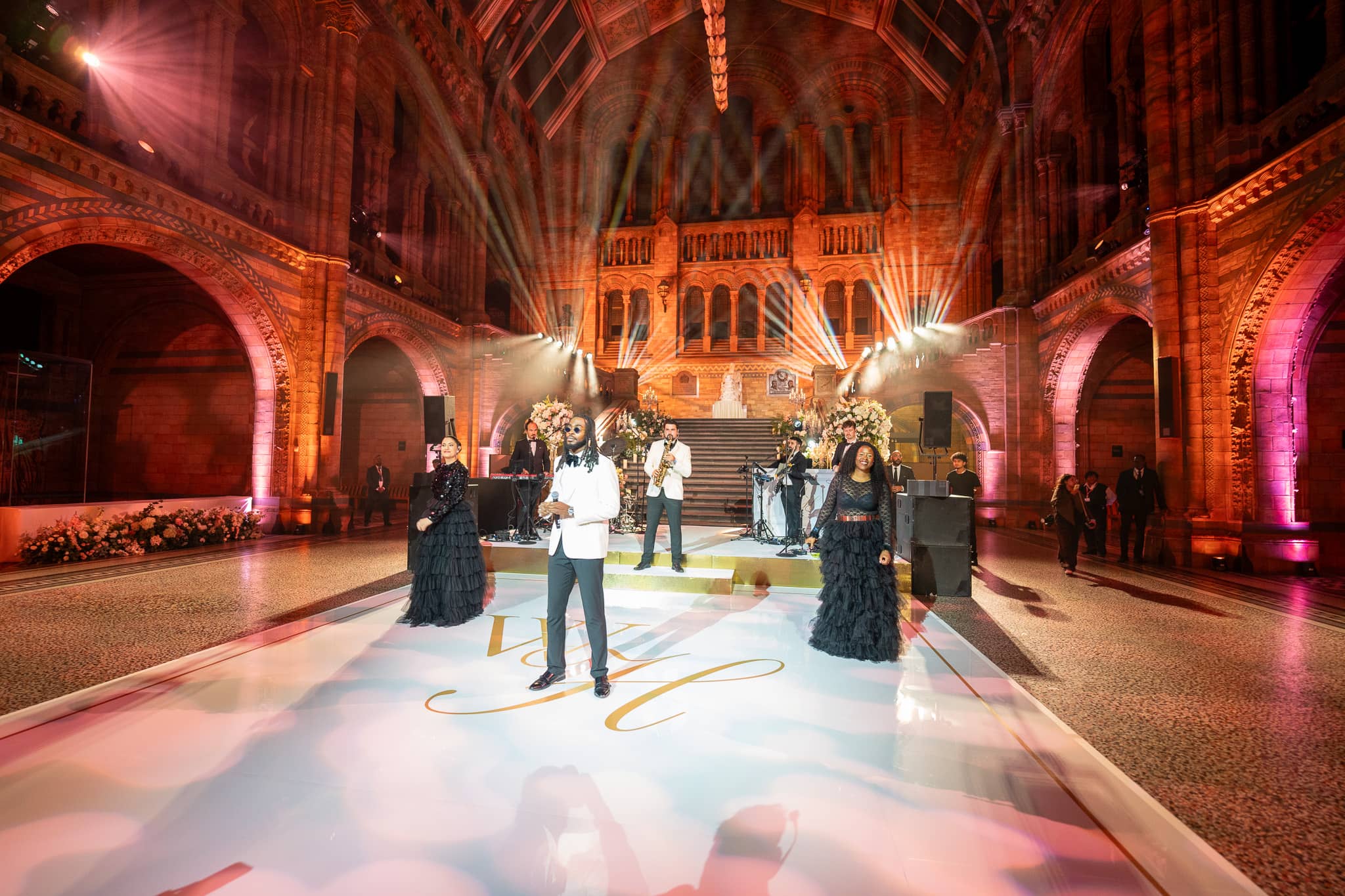 Red uplighting across Hintze Hall with the team at work before the party, at a Natural History Museum wedding lit by Kudos AV.
