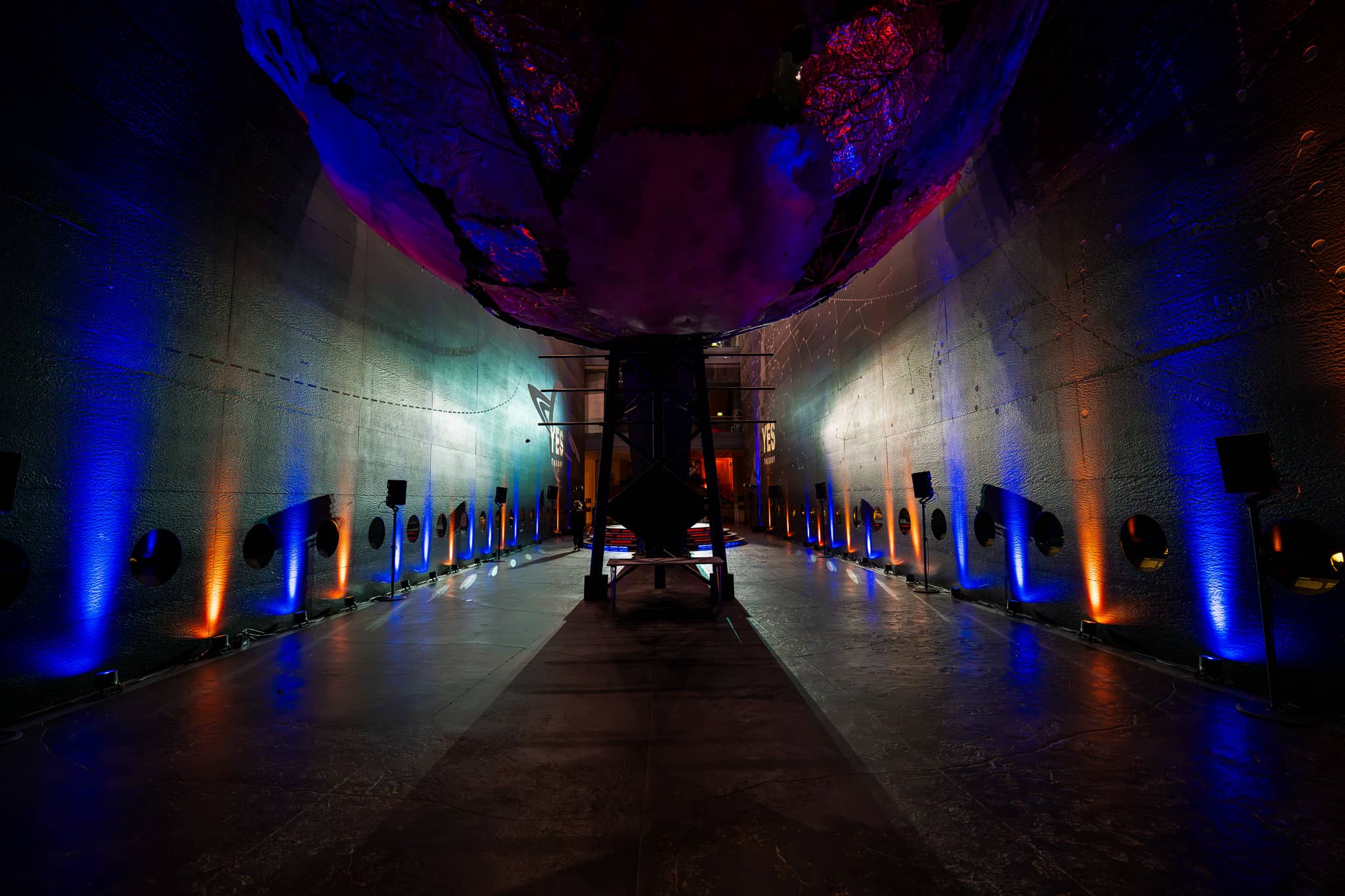 Blue and amber Astera uplighting up the walls of Earth Hall at the Yes Theory 10 million subscriber celebration, Natural History Museum, lit by Kudos AV.