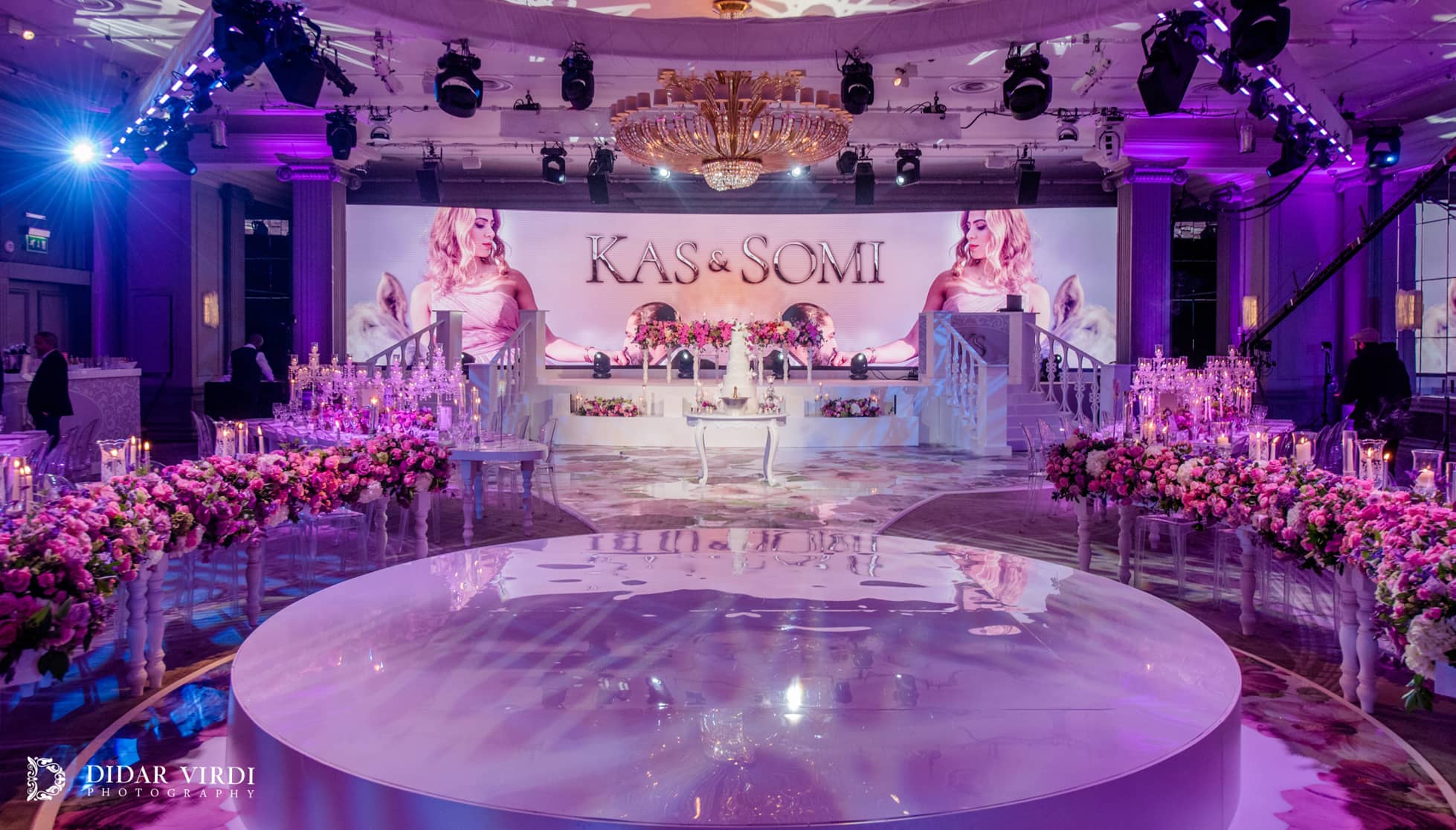 A curved LED screen displays pink floral content beyond the white circular first-dance stage at Grosvenor House London.
