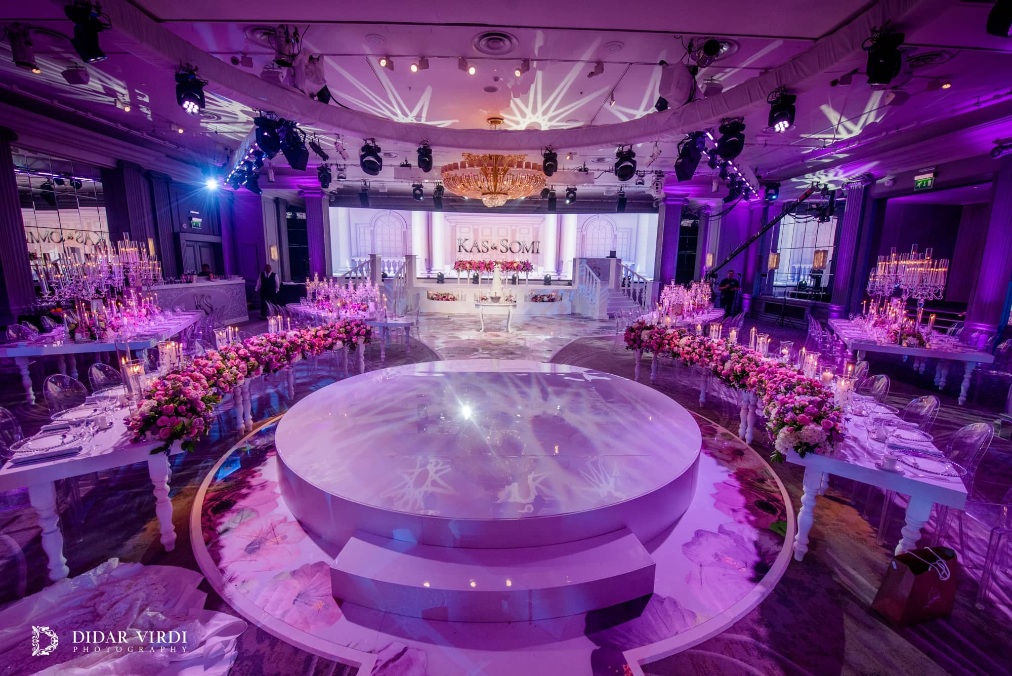 White circular stage with access steps and curved tables under purple lighting at the Grosvenor House Ballroom wedding reception.