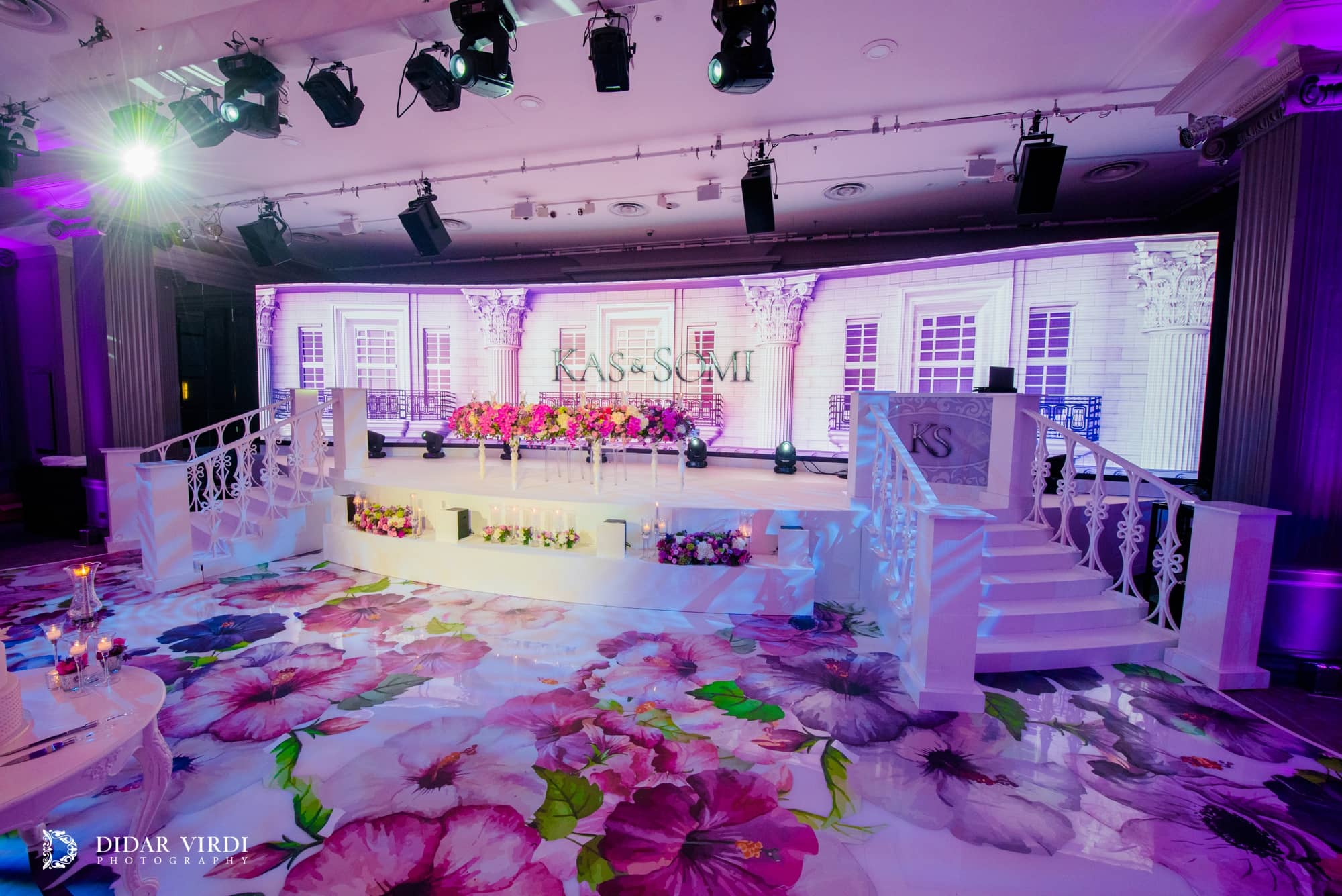 Large floral graphics across the walkway lead to the white curved stage and Italian-inspired staircase set at Grosvenor House.