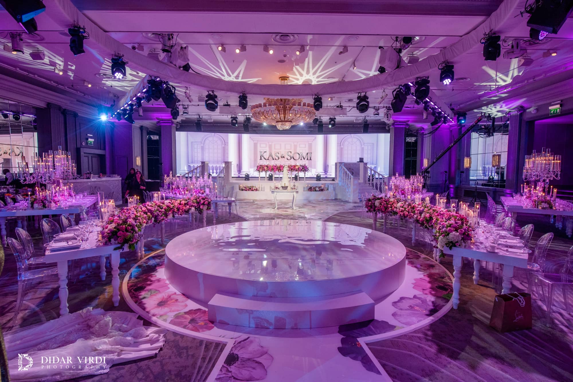 White circular first-dance stage between curved tables, aligned with the staircase set and curved LED screen in the Grosvenor House Ballroom.