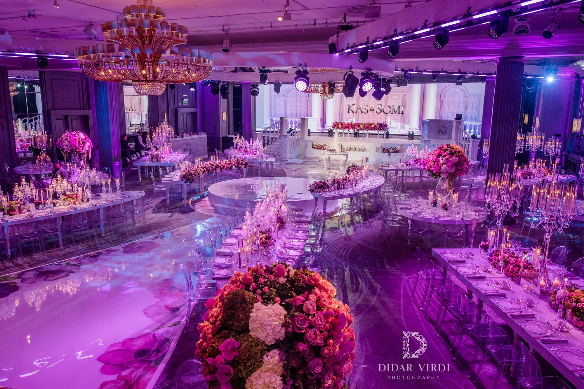 A floral walkway runs between curved dining tables towards the circular first-dance stage and white set at Grosvenor House London.