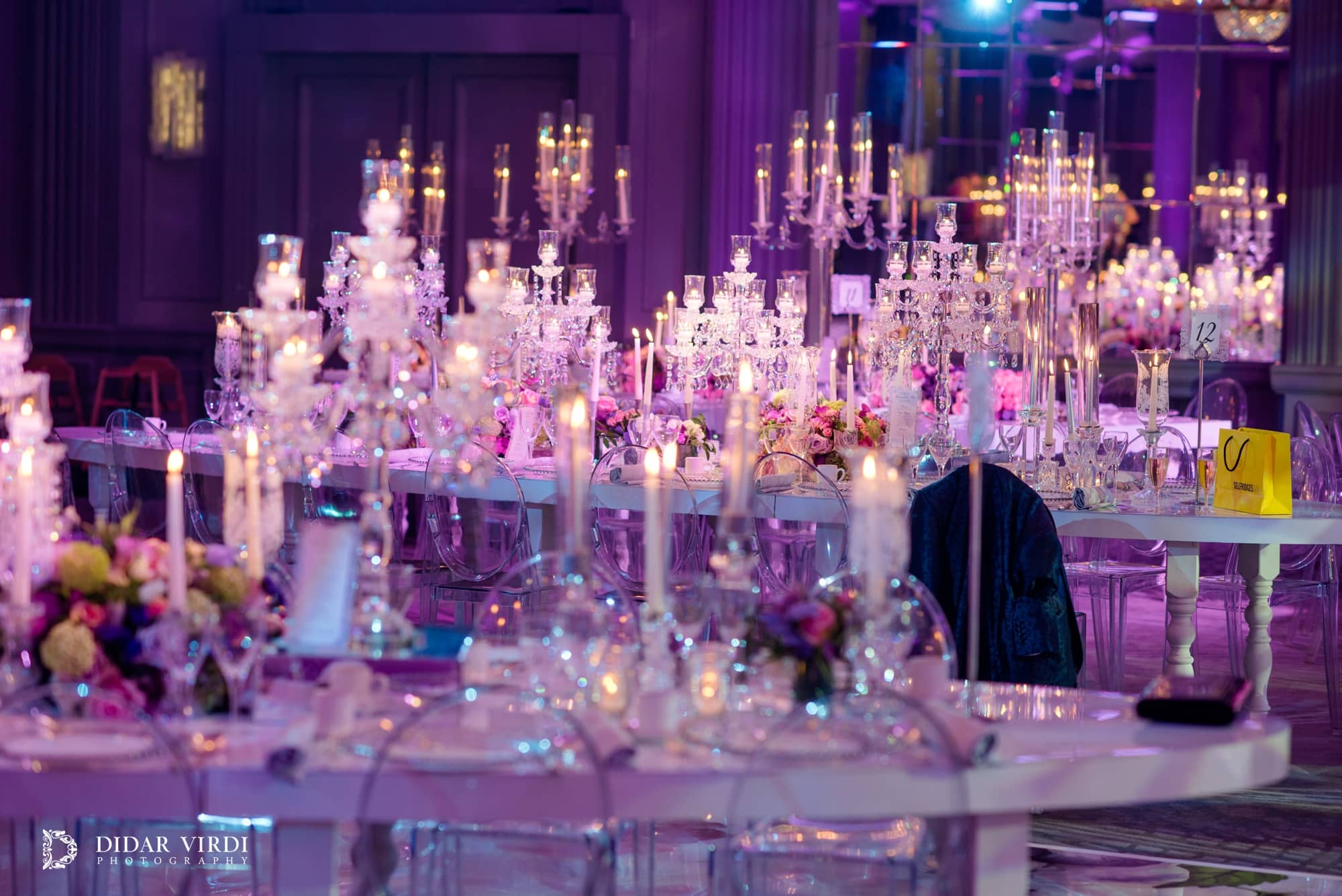 Candlelit bespoke table surfaces with glassware and flowers under a purple colour wash at Grosvenor House London.