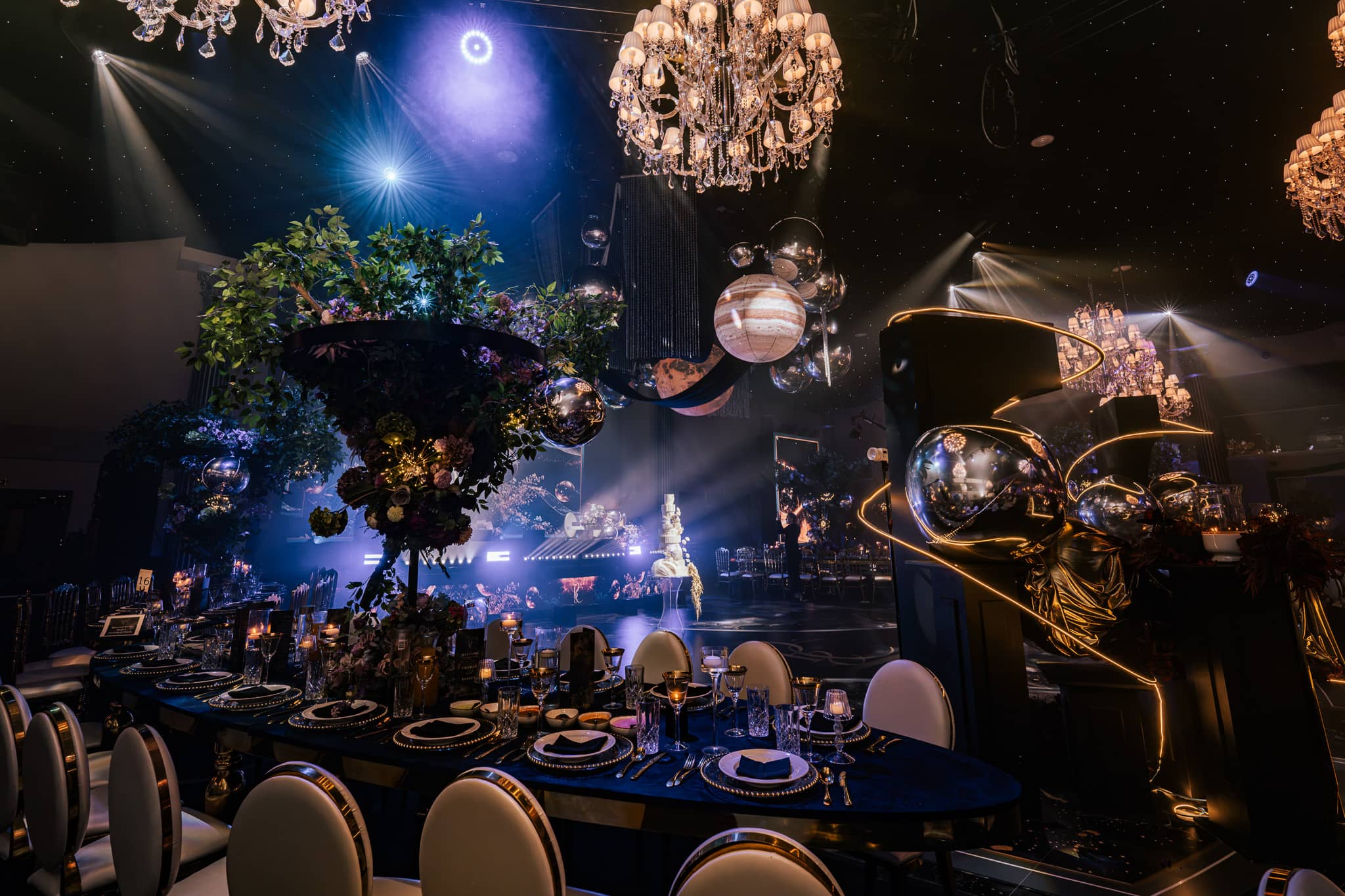 A black table with gold edging in blue light, golden sculptural pieces above, by Kudos AV