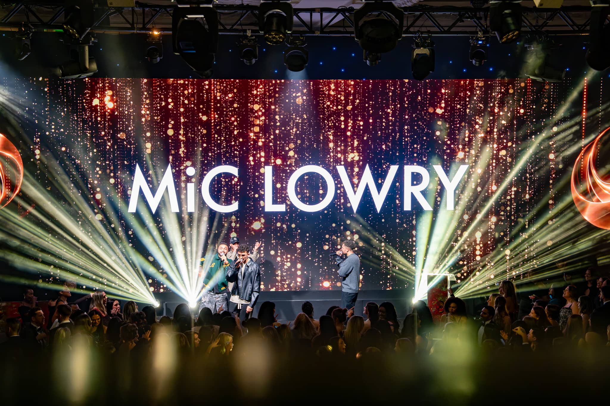 The stage from the dancefloor during MiC LOWRY’s set, beams over the crowd and the LED wall behind, Dental Beauty Partners Awards 2025 in the Great Room at Grosvenor House London, by Kudos AV.