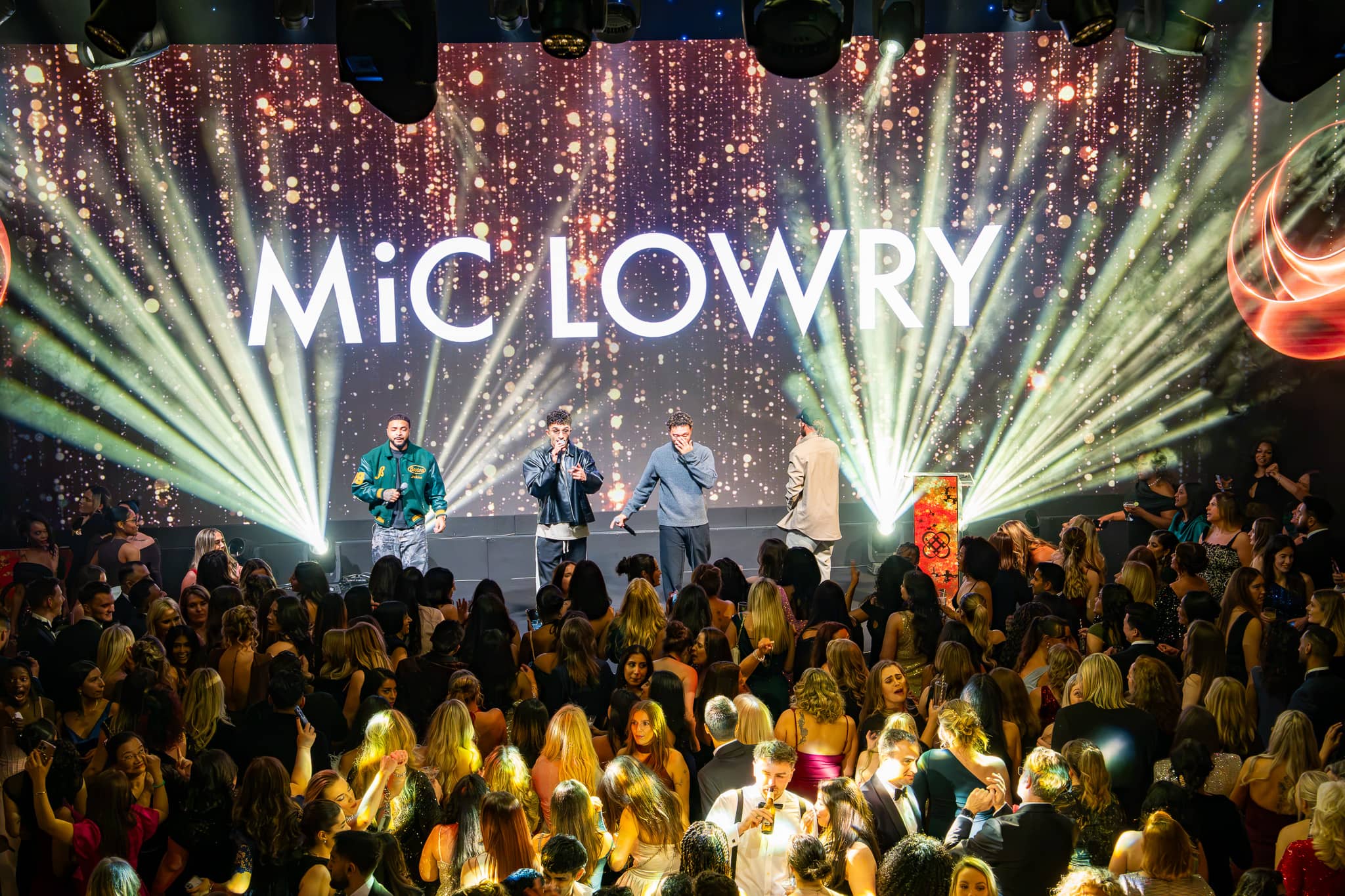Green beams and a sparkling LED backdrop behind MiC LOWRY, a packed dancefloor in front, Dental Beauty Partners Awards 2025 in the Great Room at Grosvenor House London, by Kudos AV.