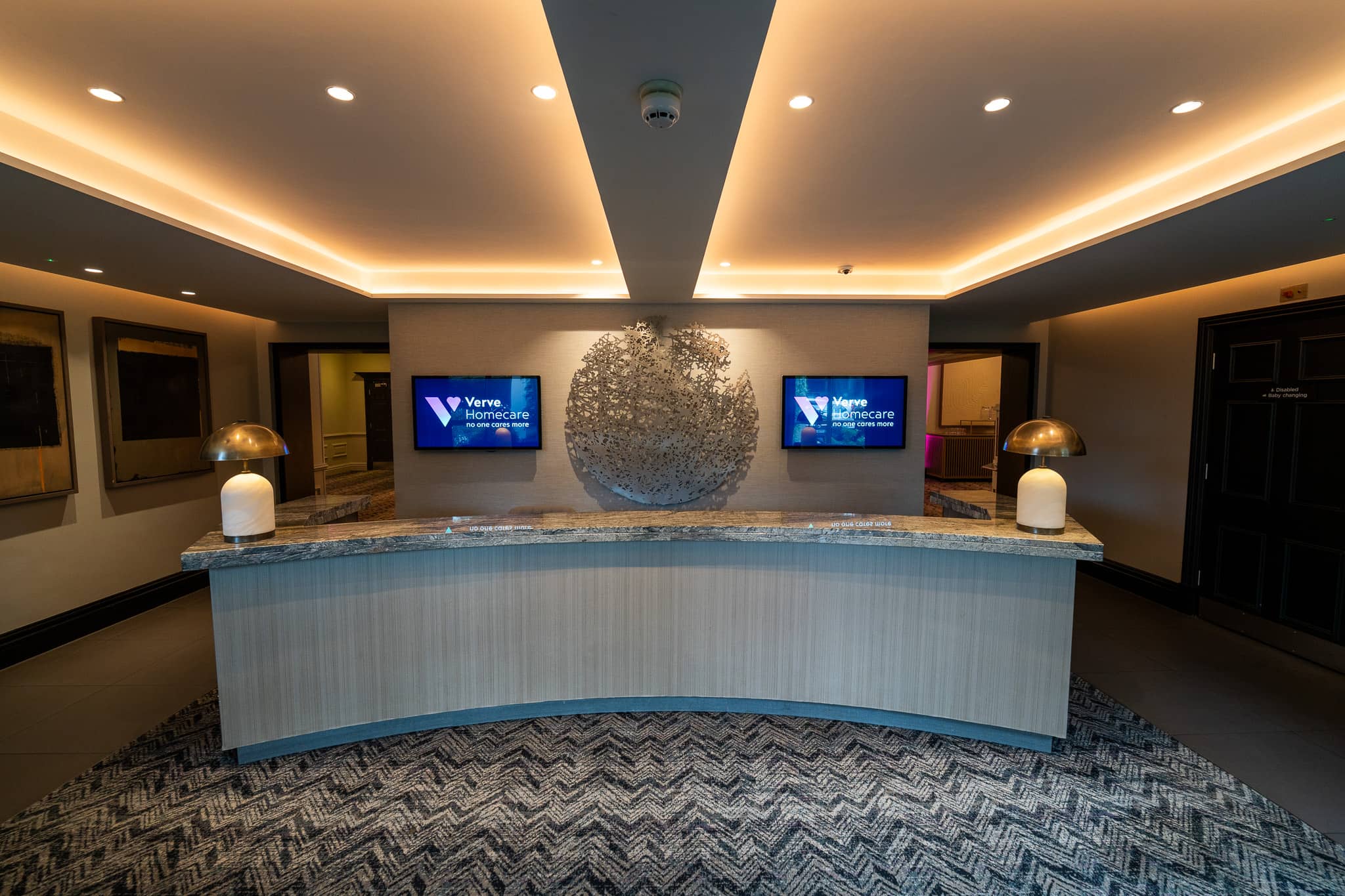 The Sopwell House conference reception desk with Verve Homecare branding on the digital signage screens for Verve Awards Night.