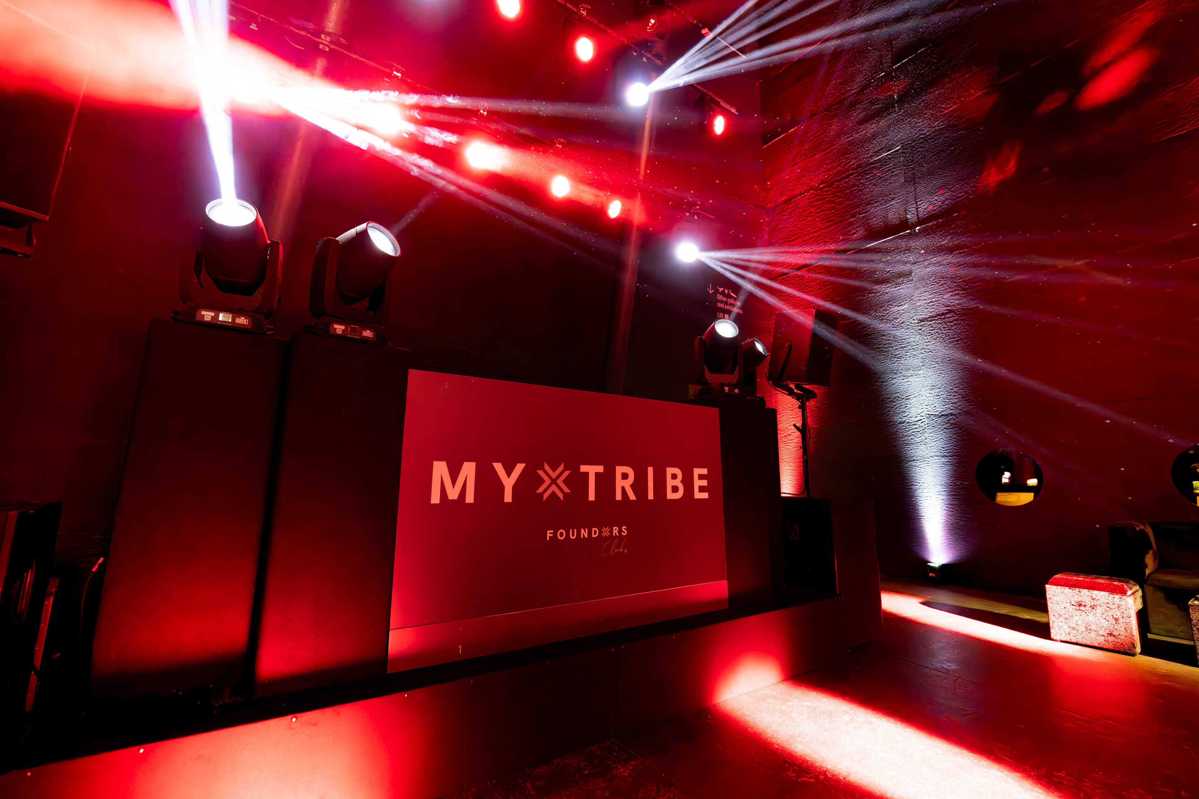 Moving head fixtures in red over the stage and the dancefloor, the screen behind, FOUNDXRS Club black tie party in Earth Hall by Kudos AV.
