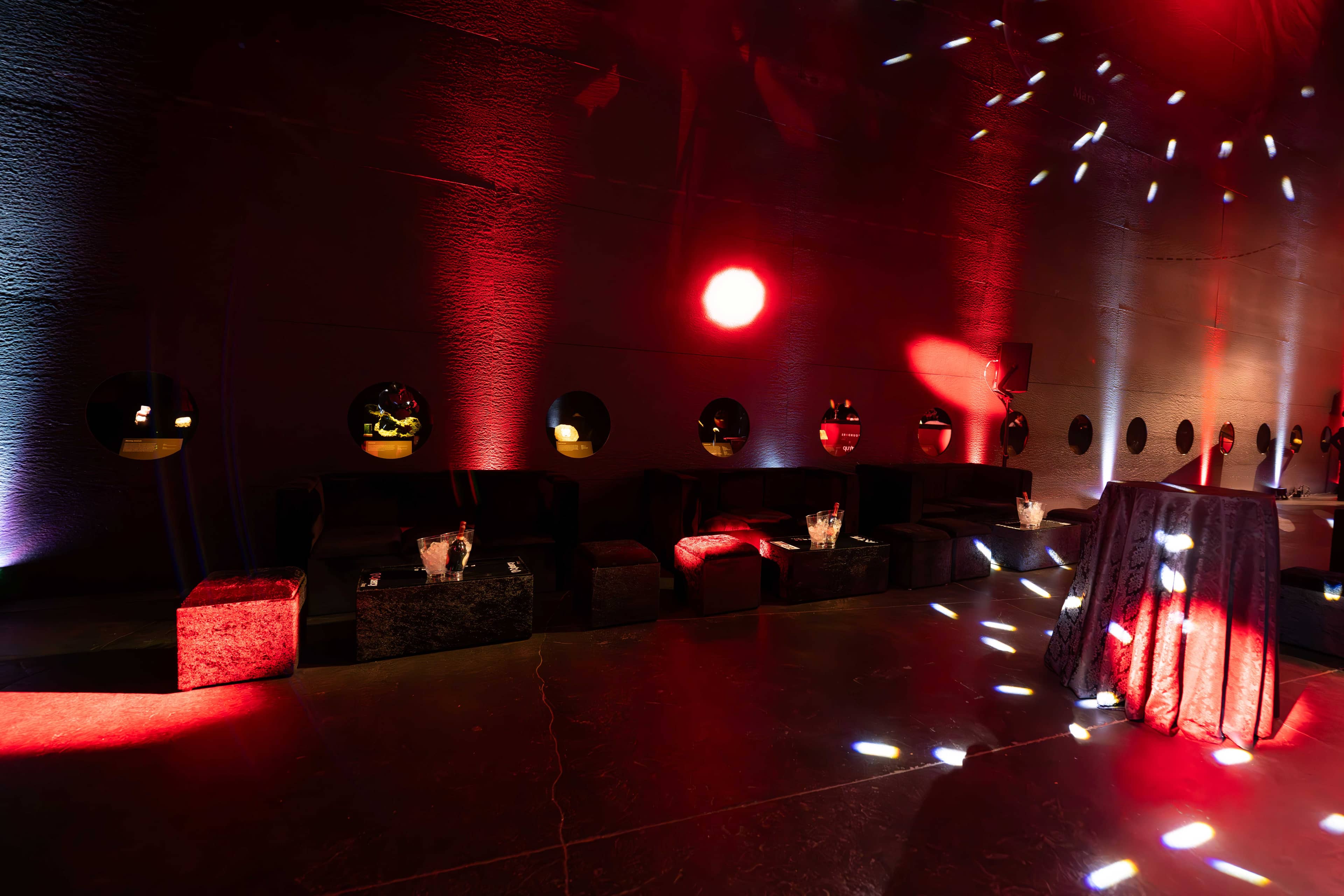 Black lounge seating lit from below under red uplighting in Earth Hall, FOUNDXRS Club black tie party by Kudos AV.