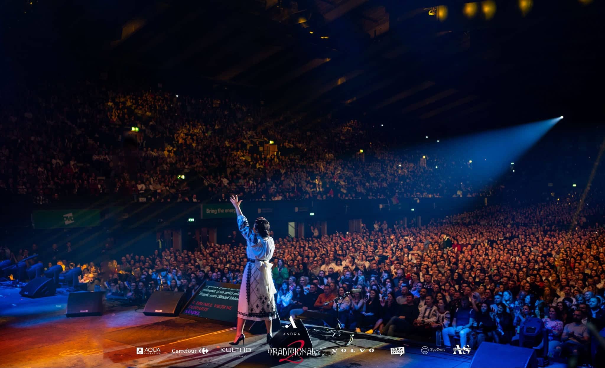 Andra raising her arm to the packed arena from the edge of the stage, side light sweeping across the audience, Andra Traditional 2 at OVO Arena Wembley, lit by Kudos AV.