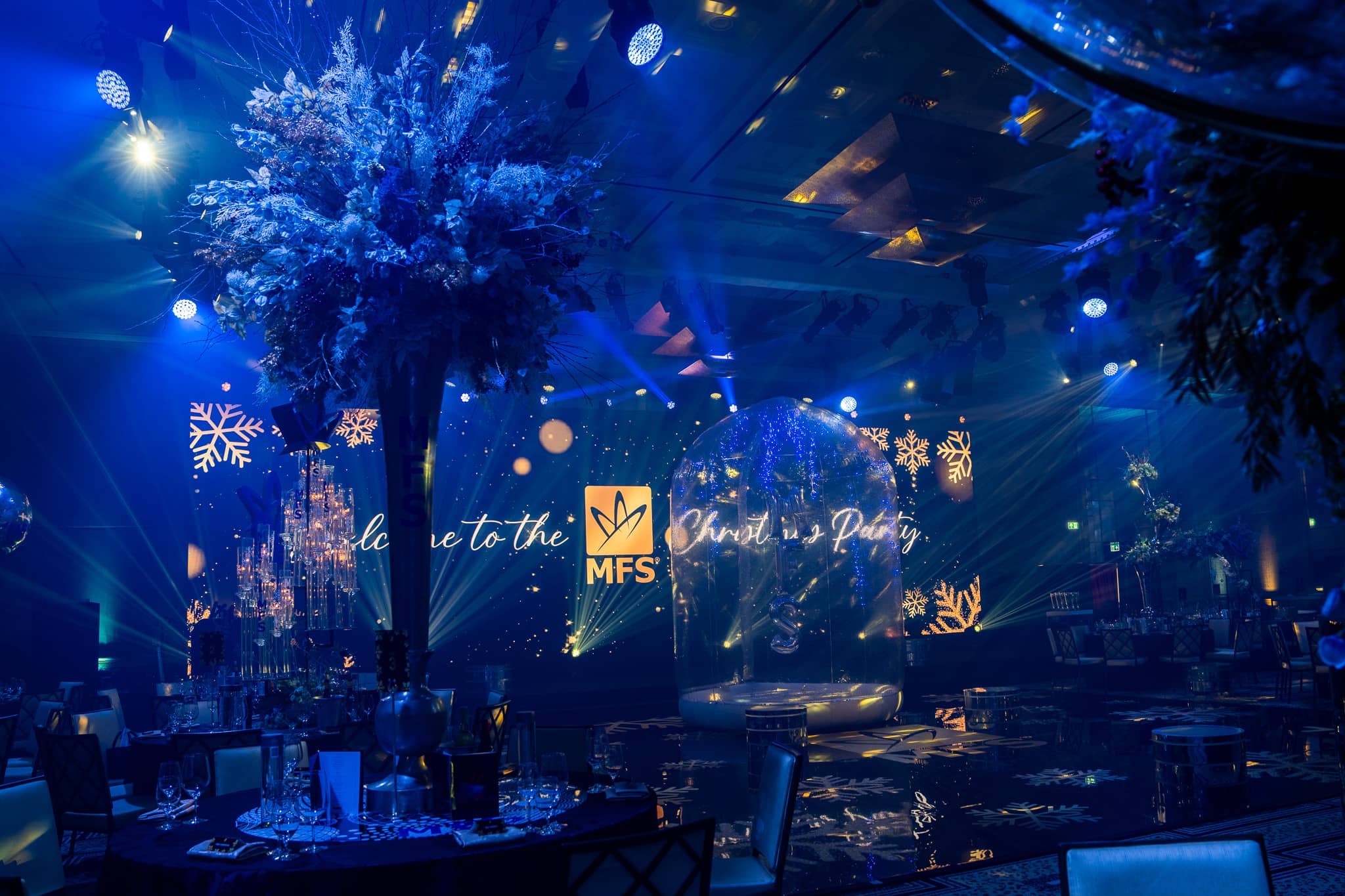 MFS Christmas party LED welcome screen seen between floral centrepieces at The Peninsula London