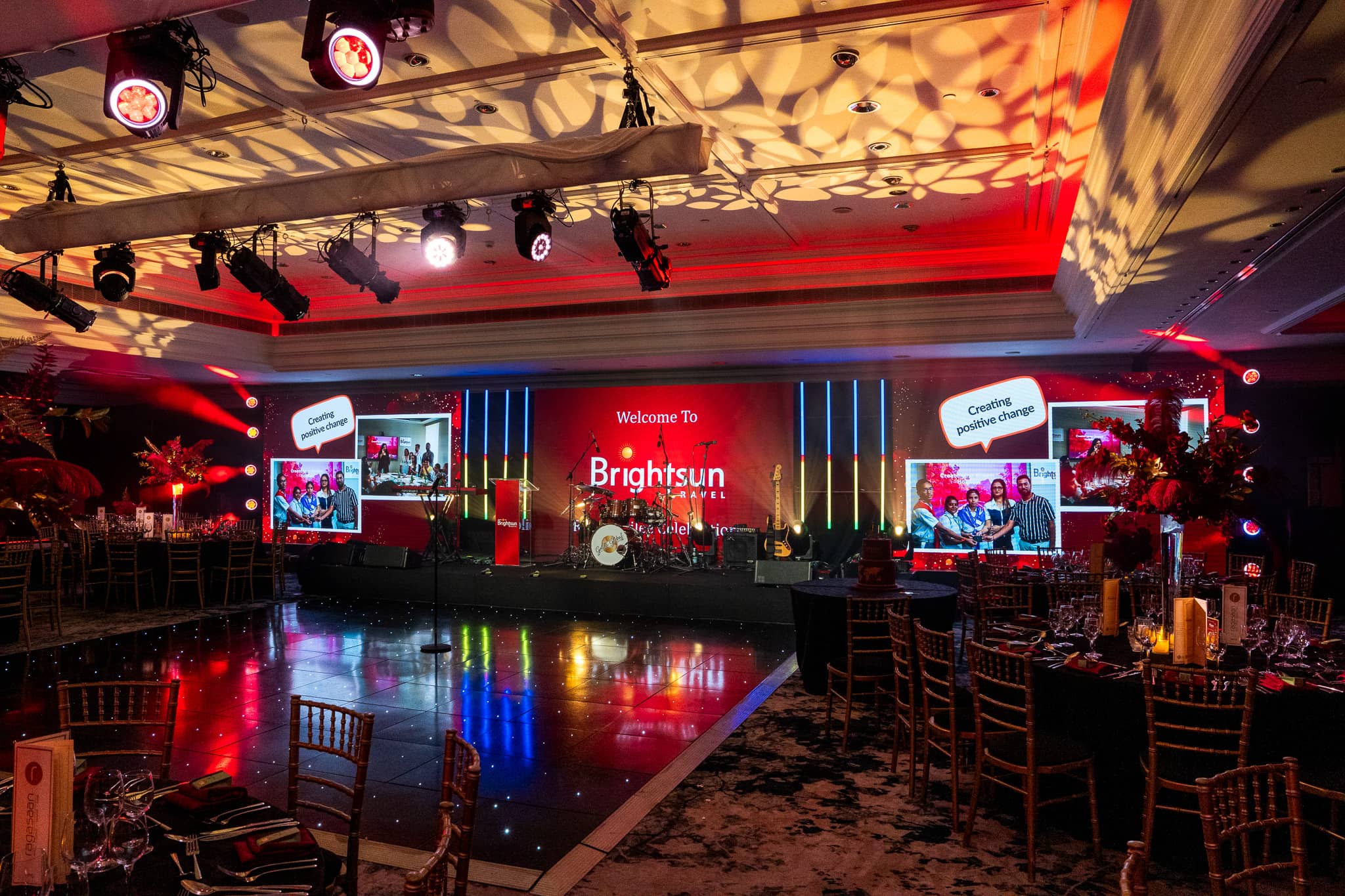 Wide stage view with Brightsun welcome graphics, photographic memories and gold ceiling patterns, at Brightsun Travel’s 40th anniversary at InterContinental London Park Lane.