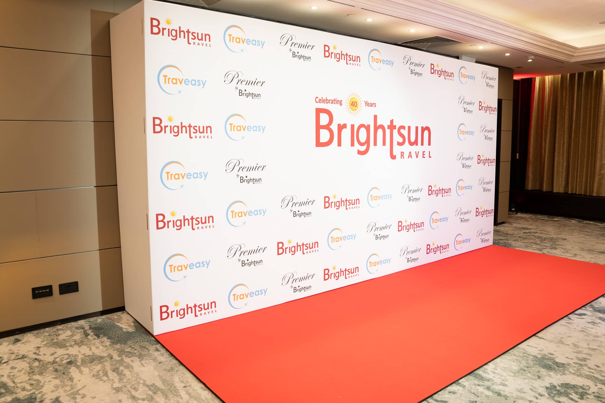 White printed Brightsun and partner-logo media wall with a red carpet, at Brightsun Travel’s 40th anniversary at InterContinental London Park Lane.