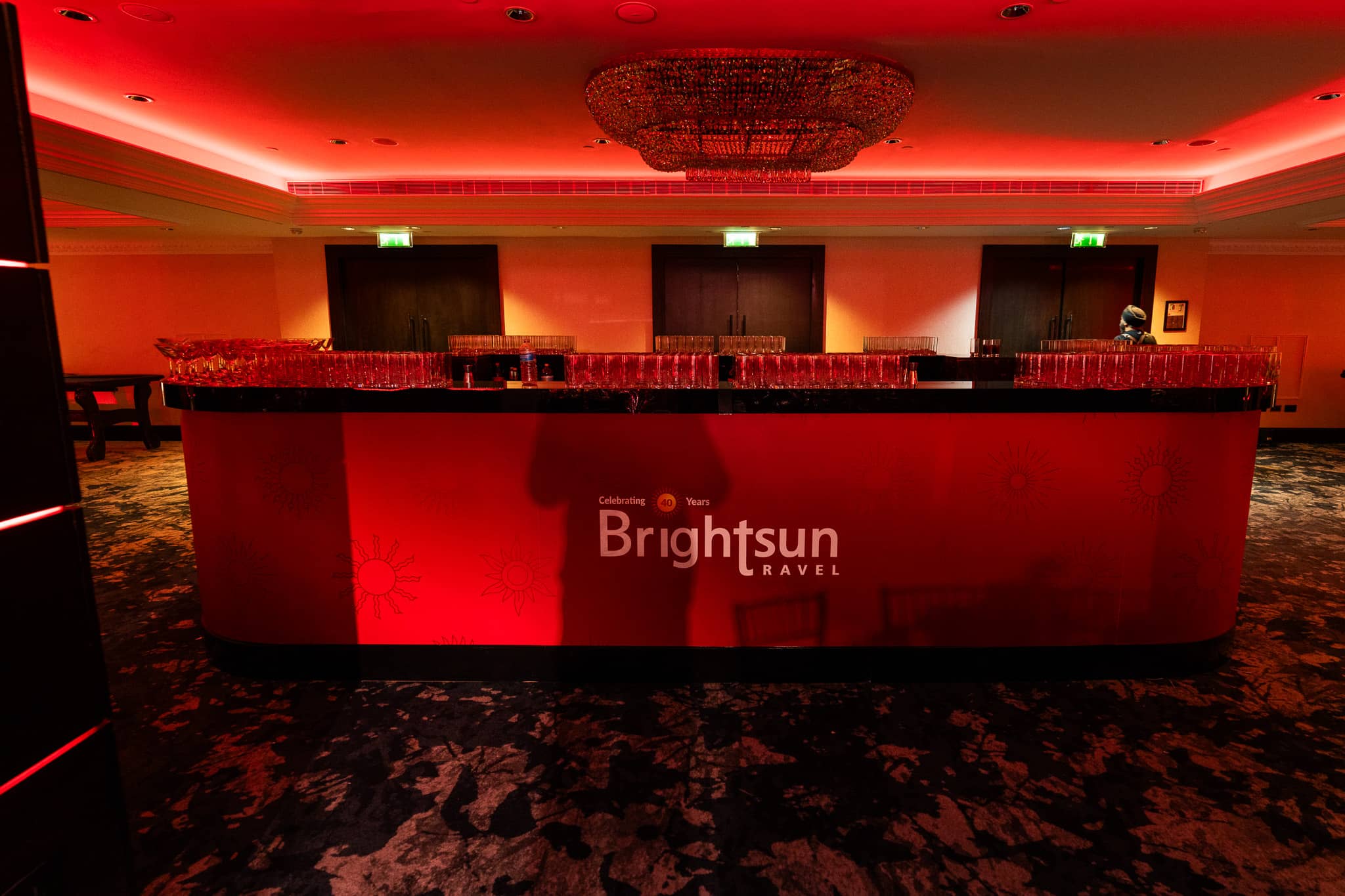 Front view of the red printed Brightsun bar and rows of glassware, at Brightsun Travel’s 40th anniversary at InterContinental London Park Lane.