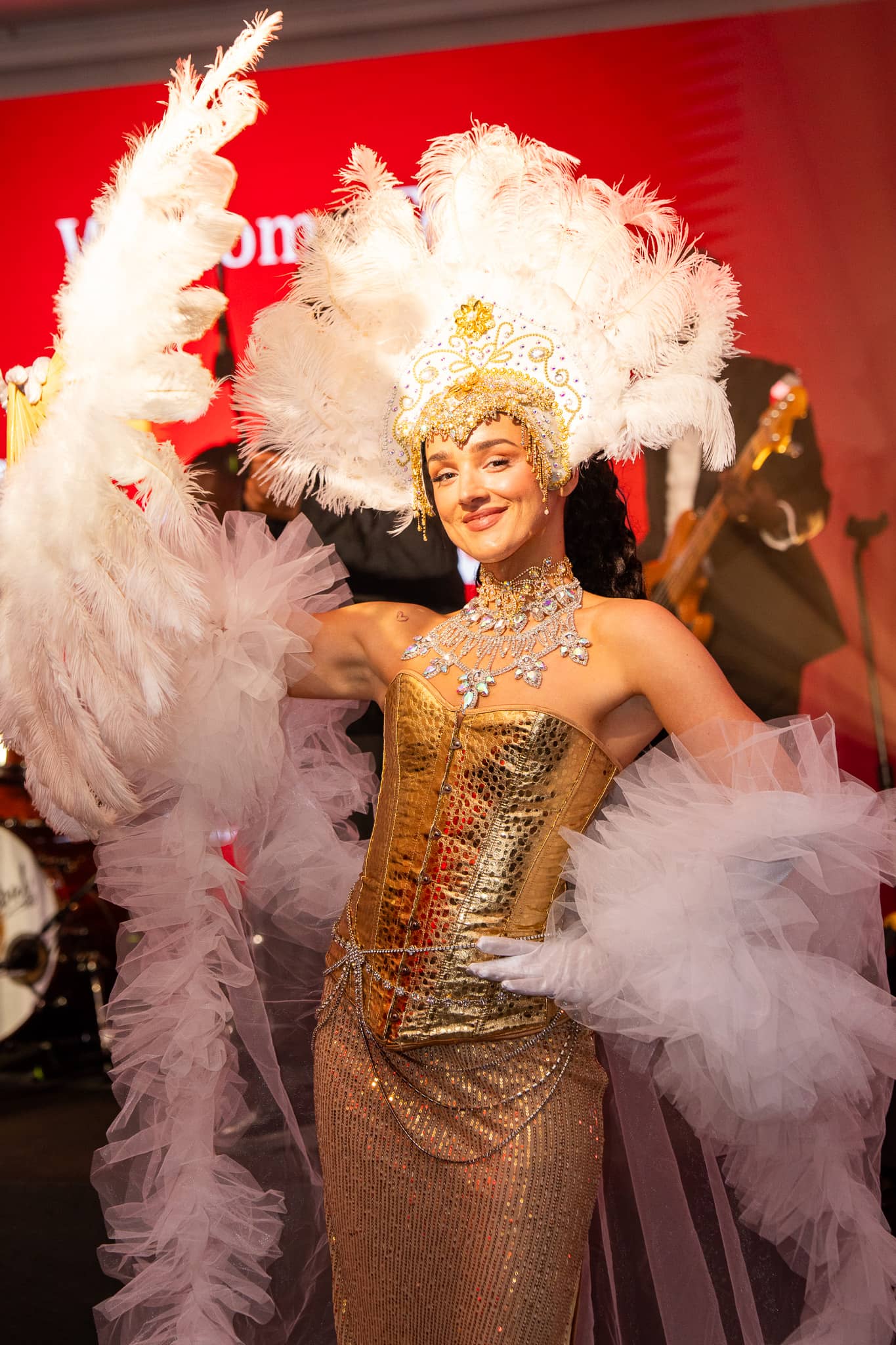 Portrait of a showgirl in a white feathered headdress and gold costume, at Brightsun Travel’s 40th anniversary at InterContinental London Park Lane.