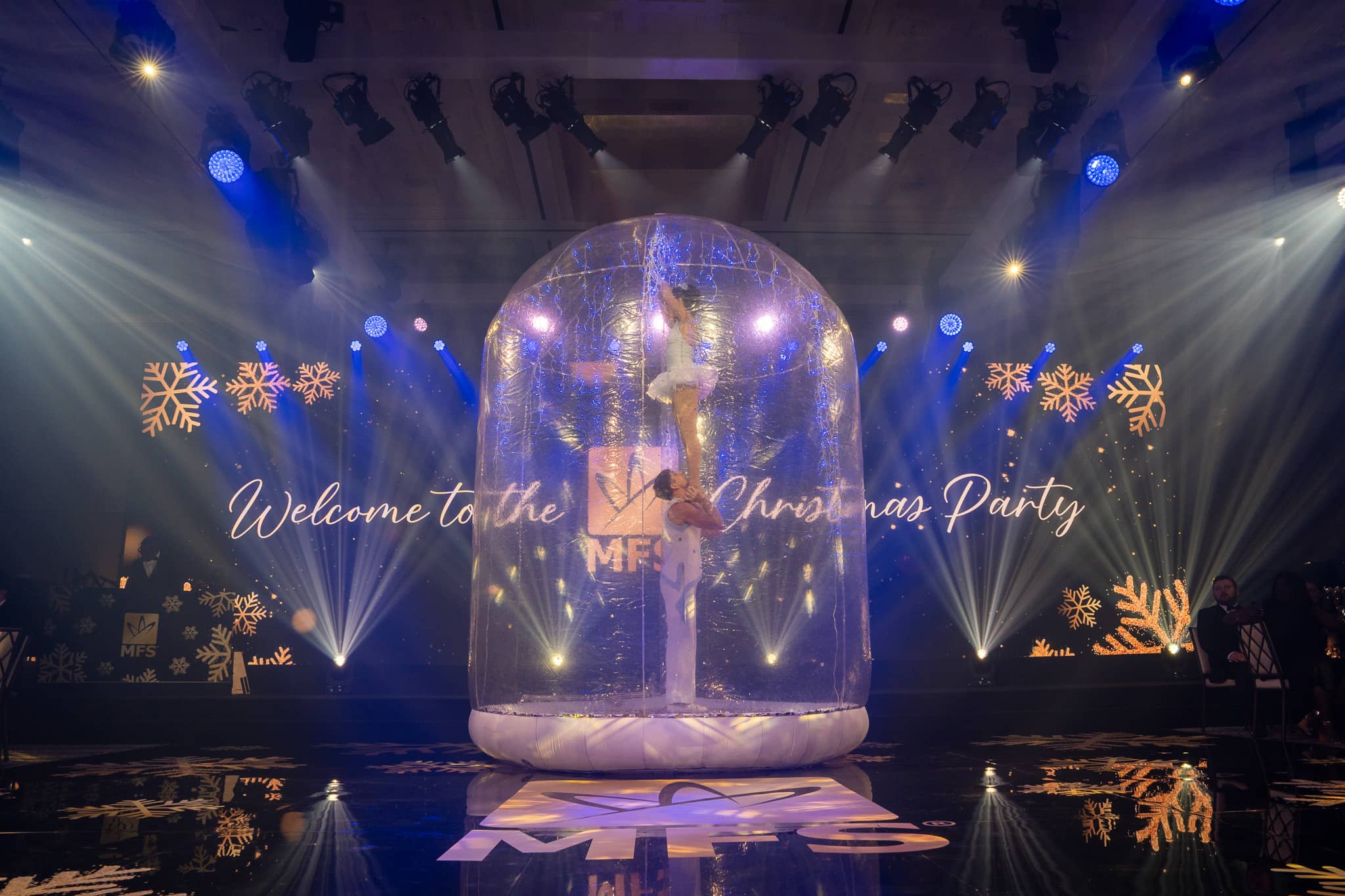 Snow-globe performer framed by blue and white lighting at the MFS Christmas party