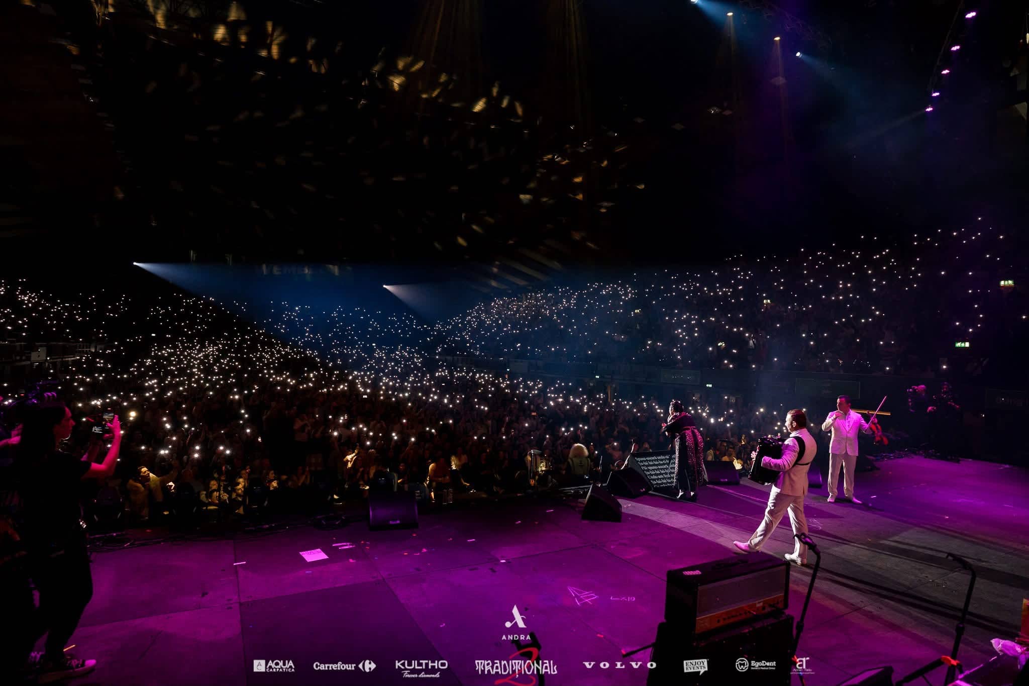 Thousands of phone lights across the arena as musicians play on a magenta lit stage, Andra Traditional 2 at OVO Arena Wembley, stage lighting by Kudos AV.