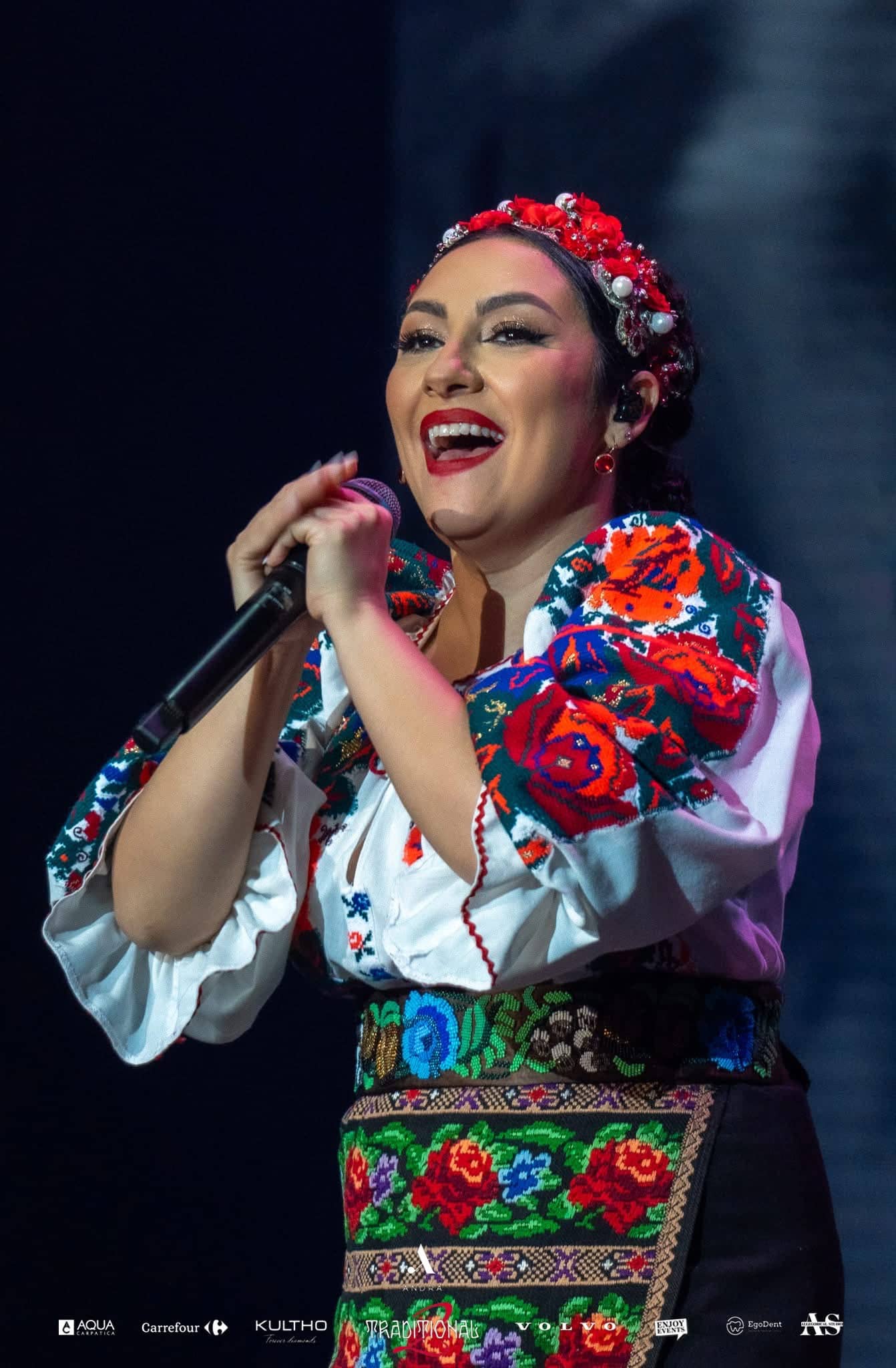 Andra singing in an embroidered Romanian blouse and floral headdress, Andra Traditional 2 at OVO Arena Wembley, stage lighting by Kudos AV.