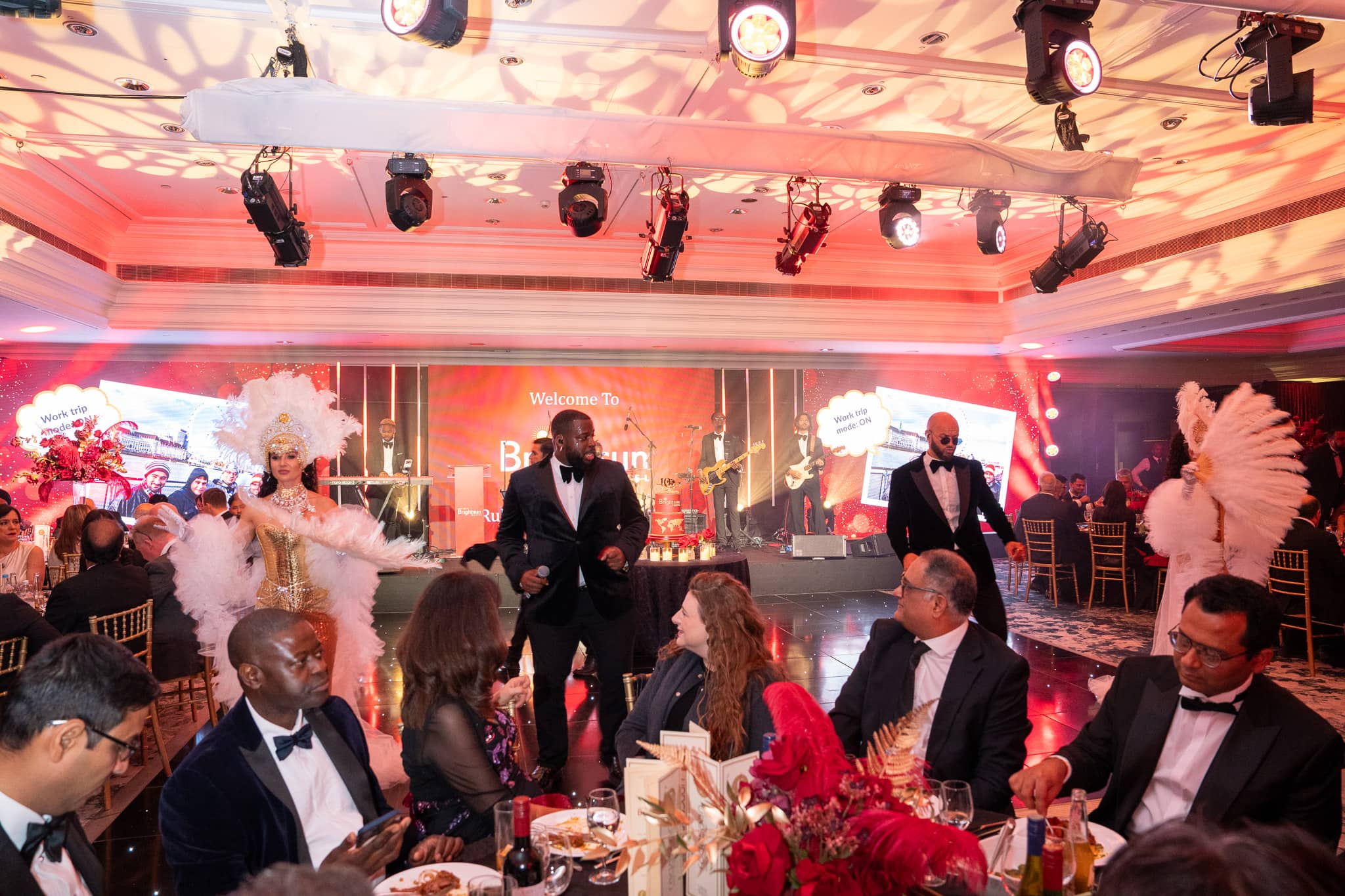 Showgirls and performers among the seated guests beneath the overhead lighting, at Brightsun Travel’s 40th anniversary at InterContinental London Park Lane.