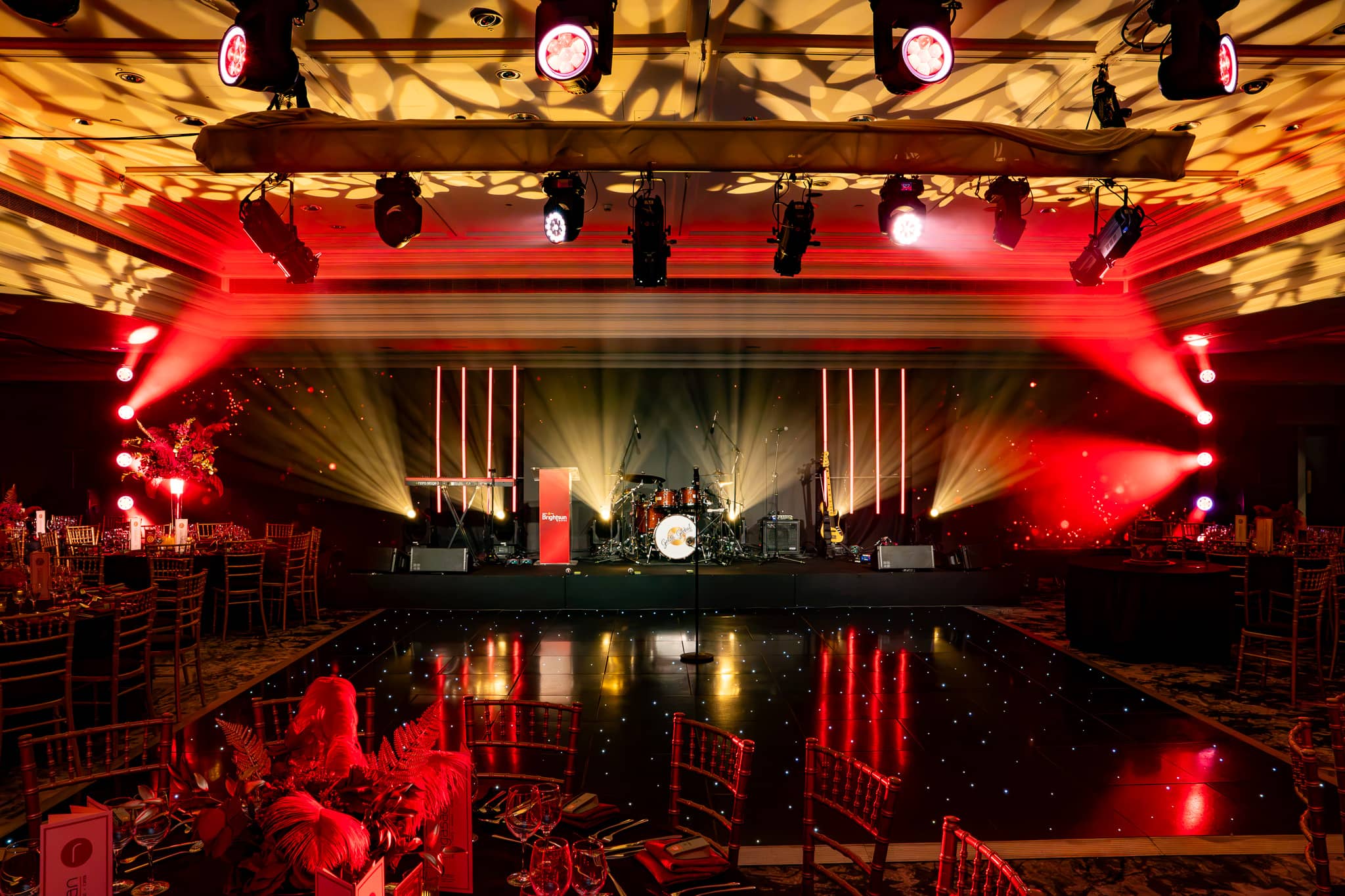 Overhead lighting casts gold patterns above the stage and glossy dancefloor, at Brightsun Travel’s 40th anniversary at InterContinental London Park Lane.