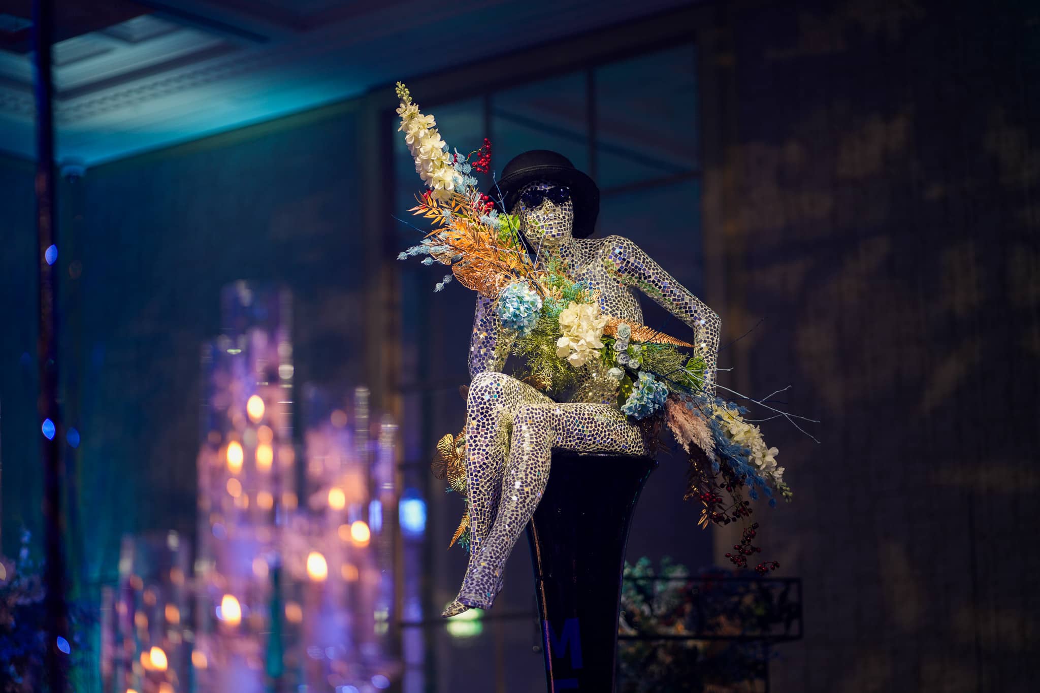 A glittering seated mannequin with flowers against blue lighting at the MFS Christmas party