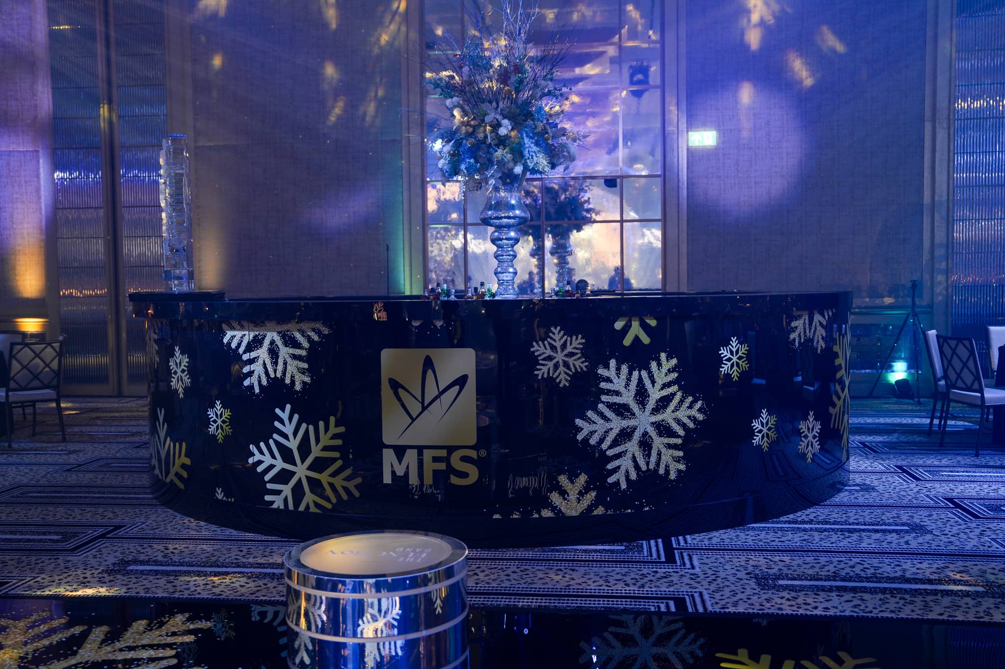 Curved printed bar with the gold MFS logo and snowflakes at The Peninsula London Christmas party